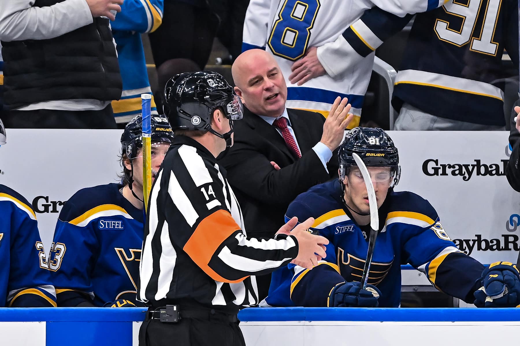 ST. LOUIS, MO - DECEMBER 17: St. Louis Blues Head Coach Jim Montgomery discusses the call on the ice with referee Trevor Hanson (14) during a regular season game where the St. Louis Blues hosted the New Jersey Devils on Tuesday December 17, 2024, at the Enterprise Center in St. Louis MO (Photo by Rick Ulreich/Icon Sportswire via Getty Images)