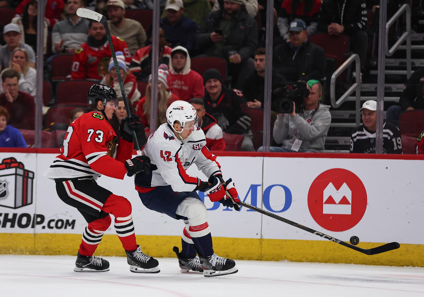 CHICAGO, IL - DECEMBER 17: Martin Fehervary #42 of the Washington Capitals controls the puck against Lukas Reichel #73 of the Chicago Blackhawks during the third period on December 17, 2024 at the United Center in Chicago, Illinois. (Photo by Melissa Tamez/Icon Sportswire via Getty Images)