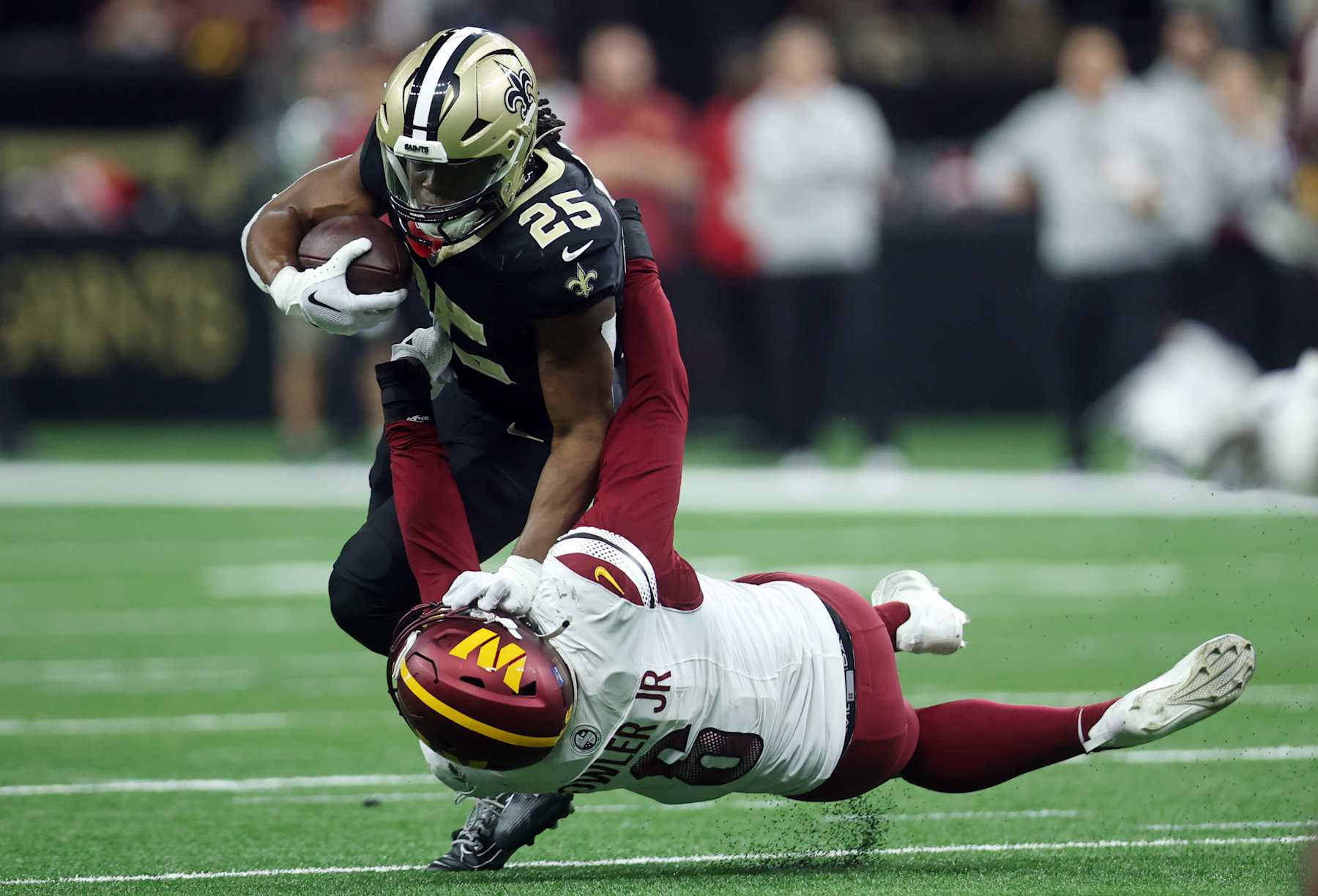 NEW ORLEANS, LOUISIANA - DECEMBER 15: Kendre Miller #25 of the New Orleans Saints is tackled by Dante Fowler Jr. #6 of the Washington Commanders during the second half at Caesars Superdome on December 15, 2024 in New Orleans, Louisiana. (Photo by Chris Graythen/Getty Images)
