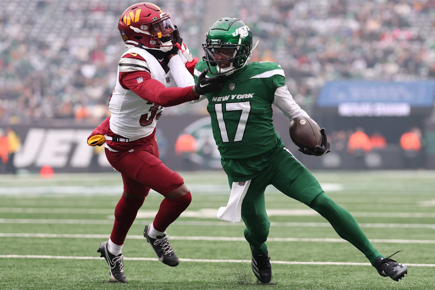 EAST RUTHERFORD, NEW JERSEY - DECEMBER 24: Garrett Wilson #17 of the New York Jets is pushed out of bounds by Percy Butler #35 of the Washington Commanders during the first quarter at MetLife Stadium on December 24, 2023 in East Rutherford, New Jersey. (Photo by Dustin Satloff/Getty Images)