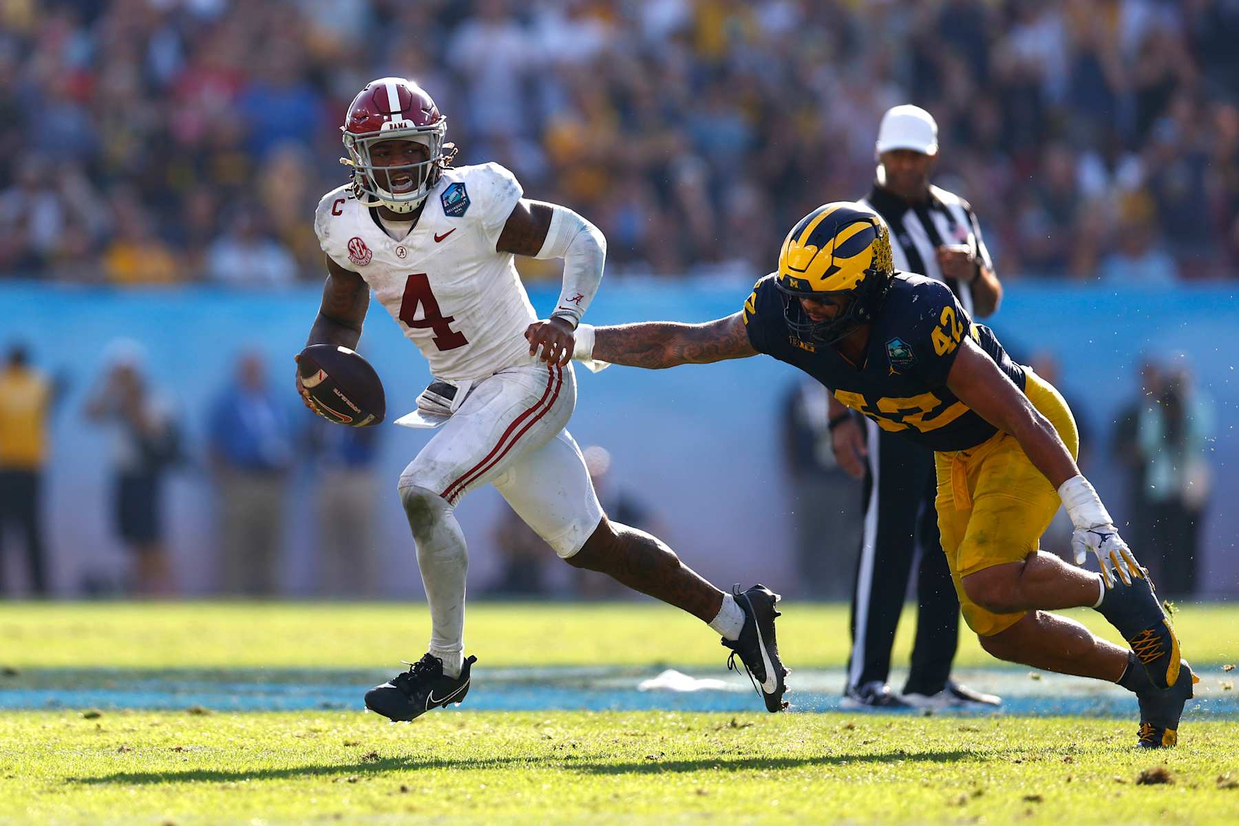 TAMPA, FLORIDA - DECEMBER 31: Jalen Milroe #4 of the Alabama Crimson Tide runs with the ball while pressured by TJ Guy #42 of the Michigan Wolverines during the fourth quarter in the 2024 ReliaQuest Bowl at Raymond James Stadium on December 31, 2024 in Tampa, Florida.  (Photo by Douglas P. DeFelice/Getty Images)