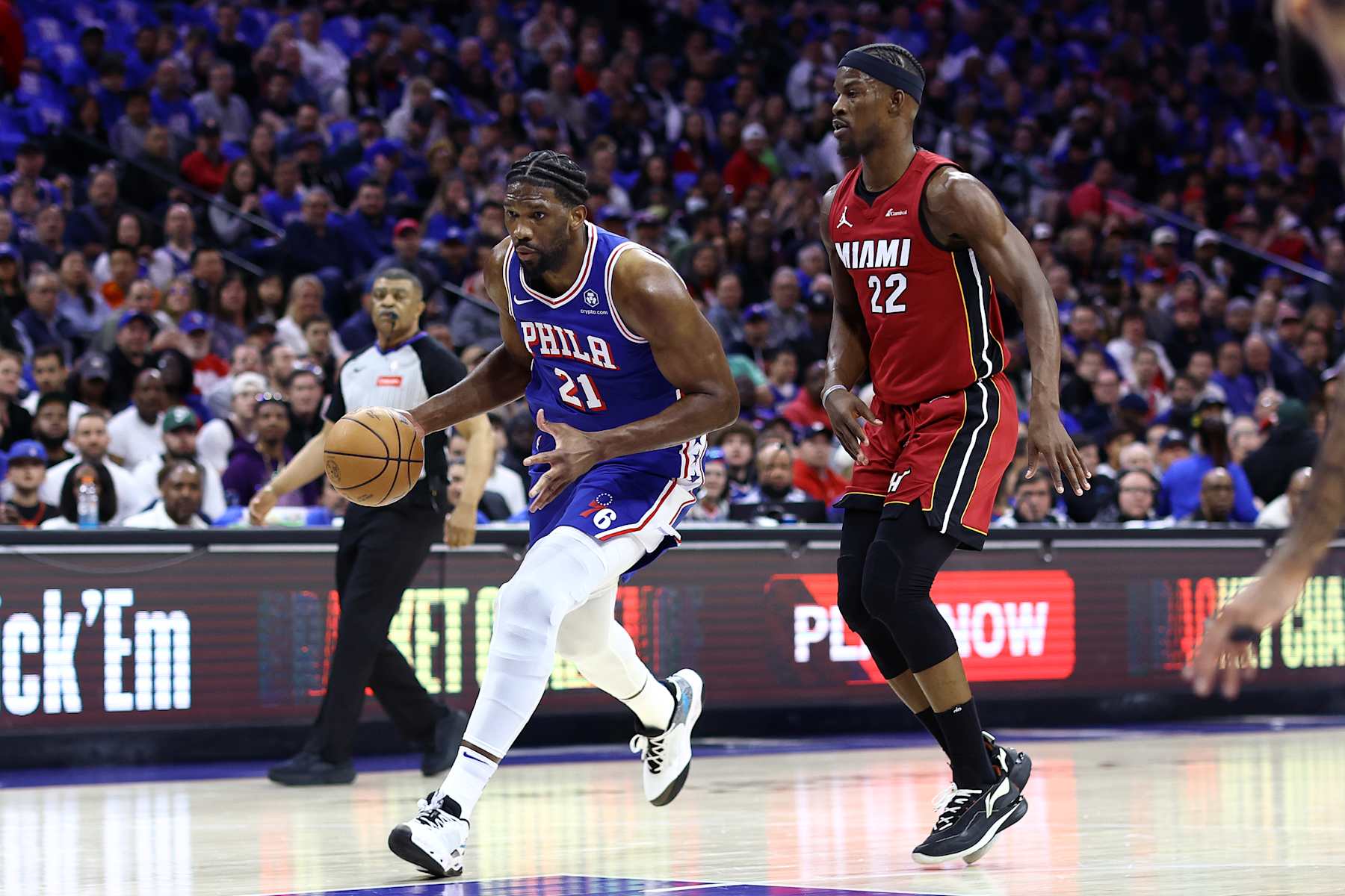 PHILADELPHIA, PENNSYLVANIA - APRIL 17: Joel Embiid #21 of the Philadelphia 76ers dribbles past Jimmy Butler #22 of the Miami Heat during the first quarter of the Eastern Conference Play-In Tournament at the Wells Fargo Center on April 17, 2024 in Philadelphia, Pennsylvania. NOTE TO USER: User expressly acknowledges and agrees that, by downloading and or using this photograph, User is consenting to the terms and conditions of the Getty Images License Agreement. (Photo by Tim Nwachukwu/Getty Images)