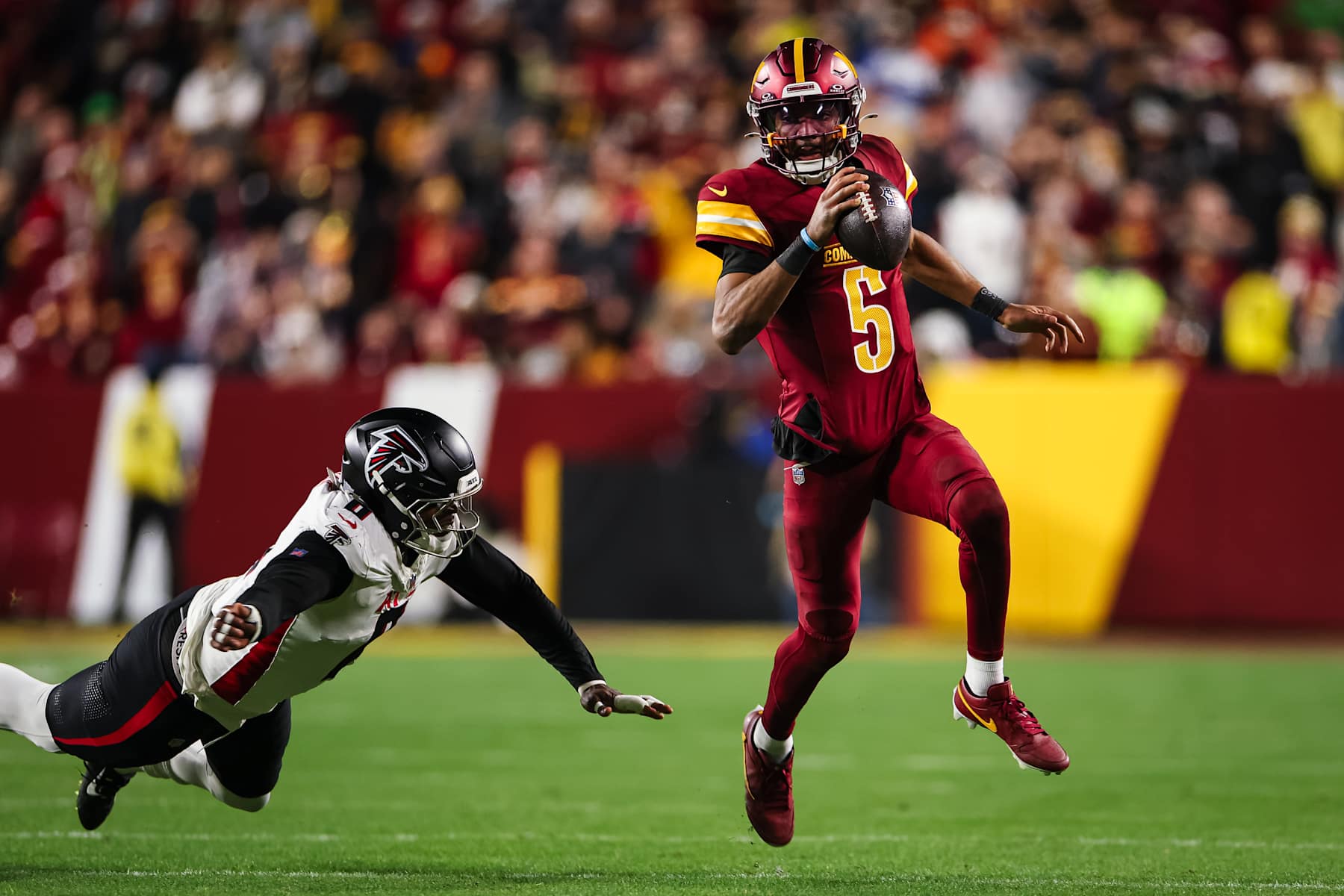 LANDOVER, MD - DECEMBER 29: Jayden Daniels #5 of the Washington Commanders carries the ball against Lorenzo Carter #0 of the Atlanta Falcons during the second half of the game at Northwest Stadium on December 29, 2024 in Landover, Maryland. (Photo by Scott Taetsch/Getty Images)