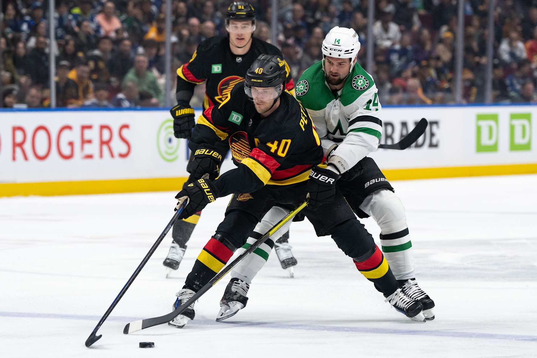 VANCOUVER, CANADA - MARCH 28: Elias Pettersson #40 of the Vancouver Canucks and Jamie Benn #14 of the Dallas Stars fight for the puck during the first period of their NHL Game at Rogers Arena on March 28, 2024 in Vancouver, British Columbia, Canada. (Photo by Ethan Cairns/Getty Images)