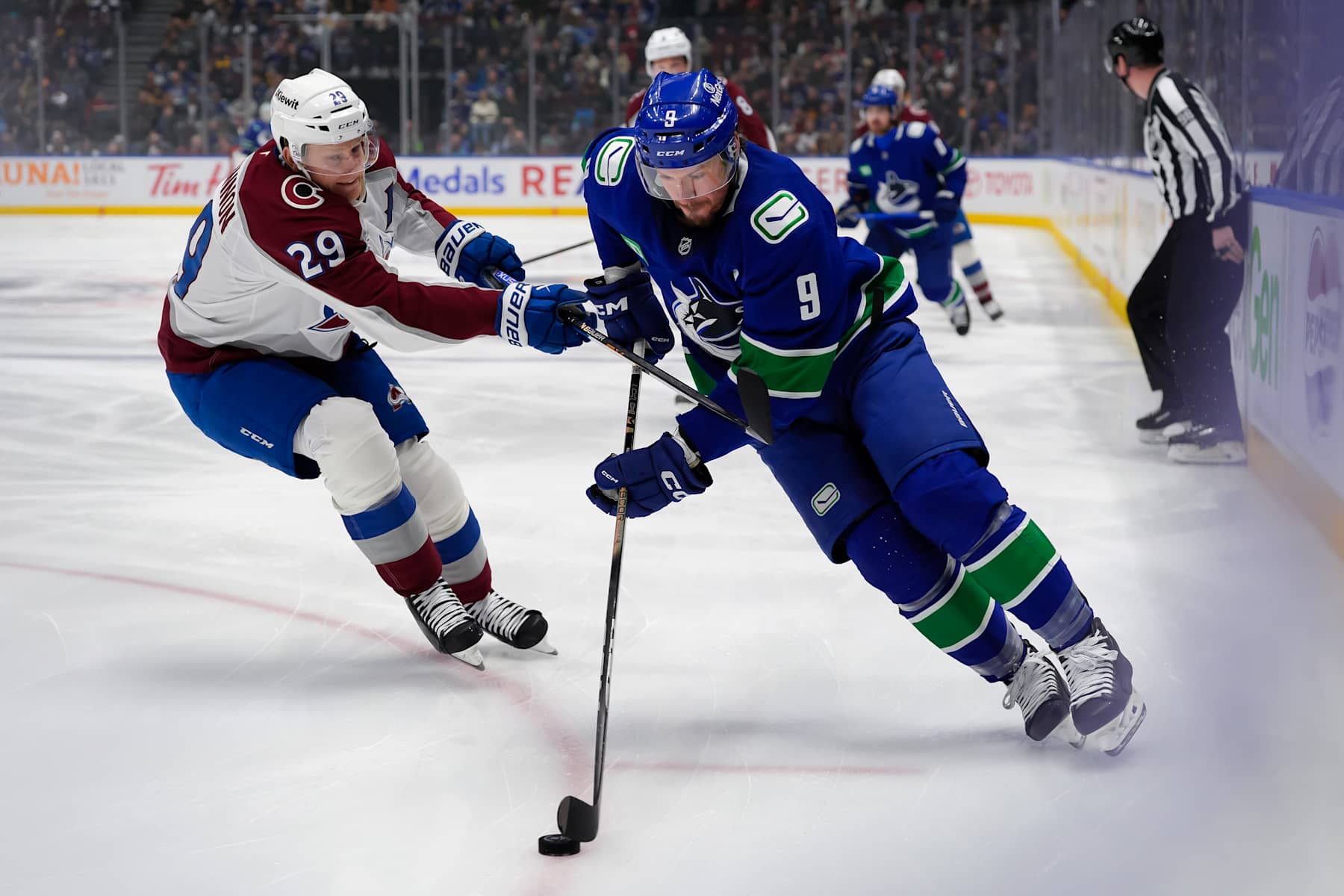 VANCOUVER, CANADA - DECEMBER 16: Nathan MacKinnon #29 of the Colorado Avalanche skates the puck against J.T. Miller #9 of the Vancouver Canucks during the first period at Rogers Arena on December 16, 2024 in Vancouver, British Columbia, Canada. (Photo by Derek Cain/Getty Images)
