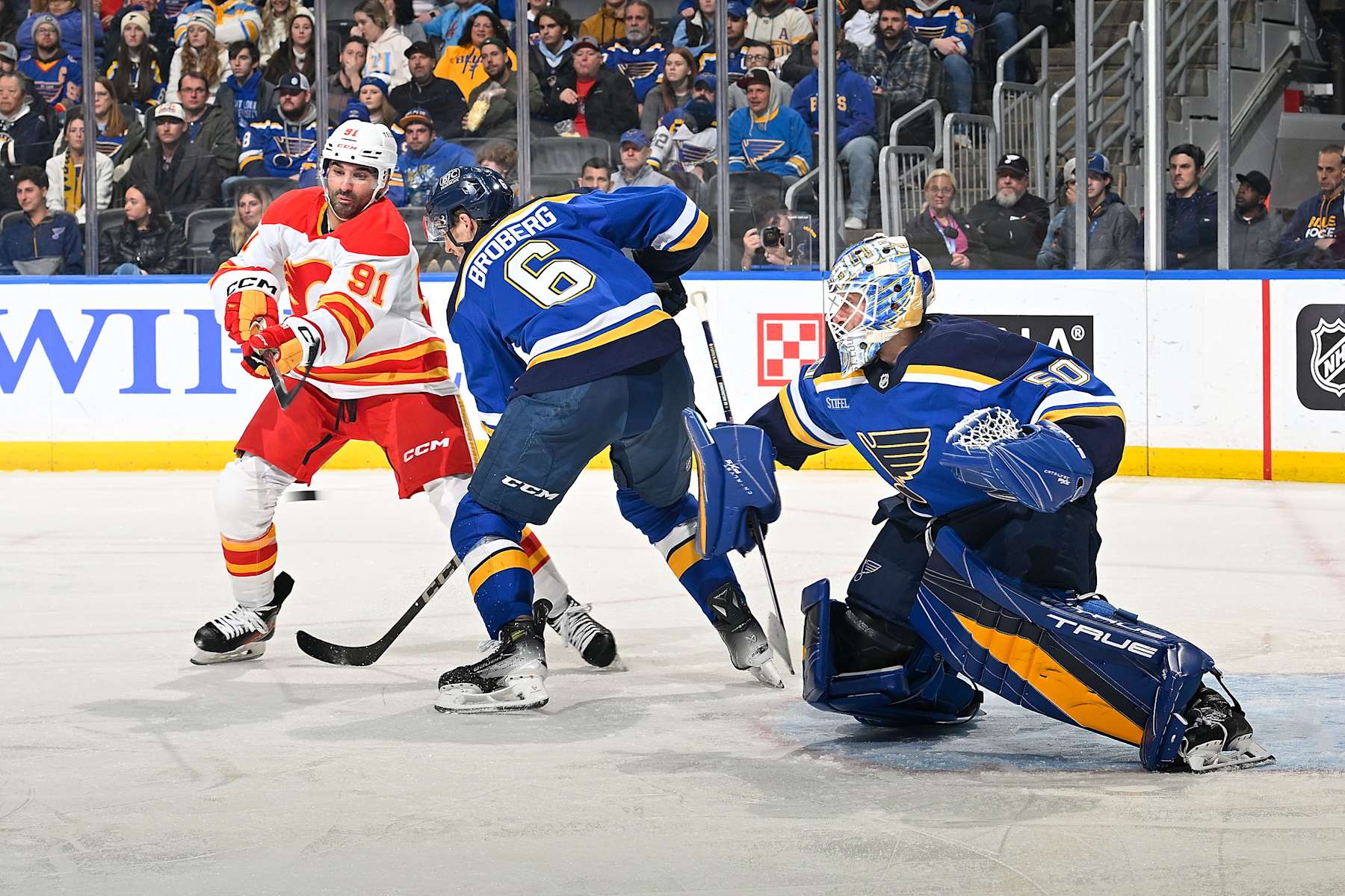 ST. LOUIS, MO - JANUARY 14: Philip Broberg #6 and Jordan Binnington #50 of the St. Louis Blues defend the net against Nazem Kadri #91 of the Calgary Flames on January 14, 2025 at the Enterprise Center in St. Louis, Missouri. (Photo by Scott Rovak/NHLI via Getty Images)
