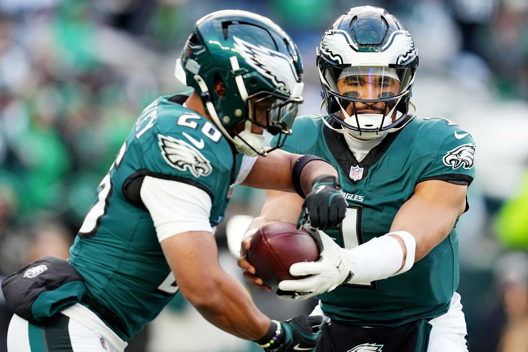 PHILADELPHIA, PENNSYLVANIA - JANUARY 12: Jalen Hurts #1  hands off to Saquon Barkley #26 of the Philadelphia Eagles prior to a game against the Green Bay Packers during the NFC Wild Card Playoff at Lincoln Financial Field on January 12, 2025 in Philadelphia, Pennsylvania.  (Photo by Mitchell Leff/Getty Images)