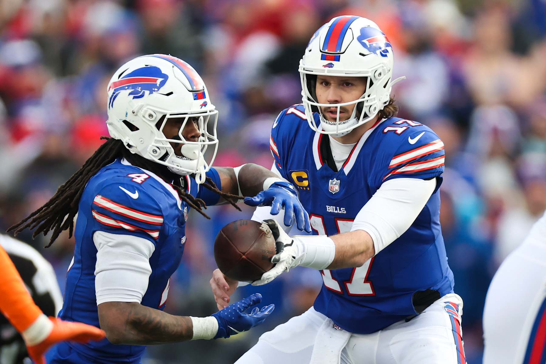 ORCHARD PARK, NEW YORK - JANUARY 12: Josh Allen #17 of the Buffalo Bills hands off the ball to teammate James Cook #4 in the third quarter against the Denver Broncos during the AFC Wild Card Playoffs at Highmark Stadium on January 12, 2025 in Orchard Park, New York. (Photo by Elsa/Getty Images)