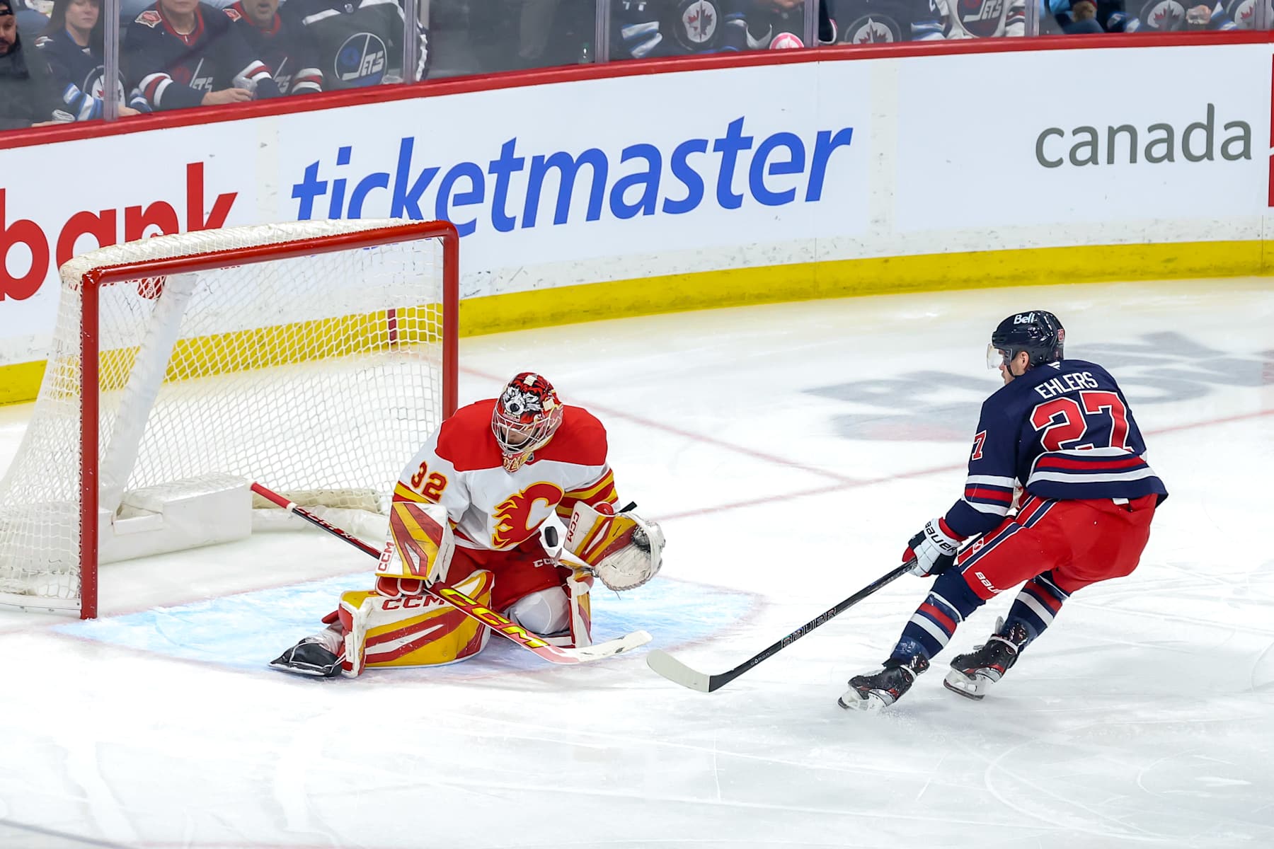 WINNIPEG, CANADA - JANUARY 18: Goaltender Dustin Wolf #32 of the Calgary Flames makes a stop on Nikolaj Ehlers #27 of the Winnipeg Jets during first period action at the Canada Life Centre on January 18, 2025 in Winnipeg, Manitoba, Canada. (Photo by Jonathan Kozub/NHLI via Getty Images)