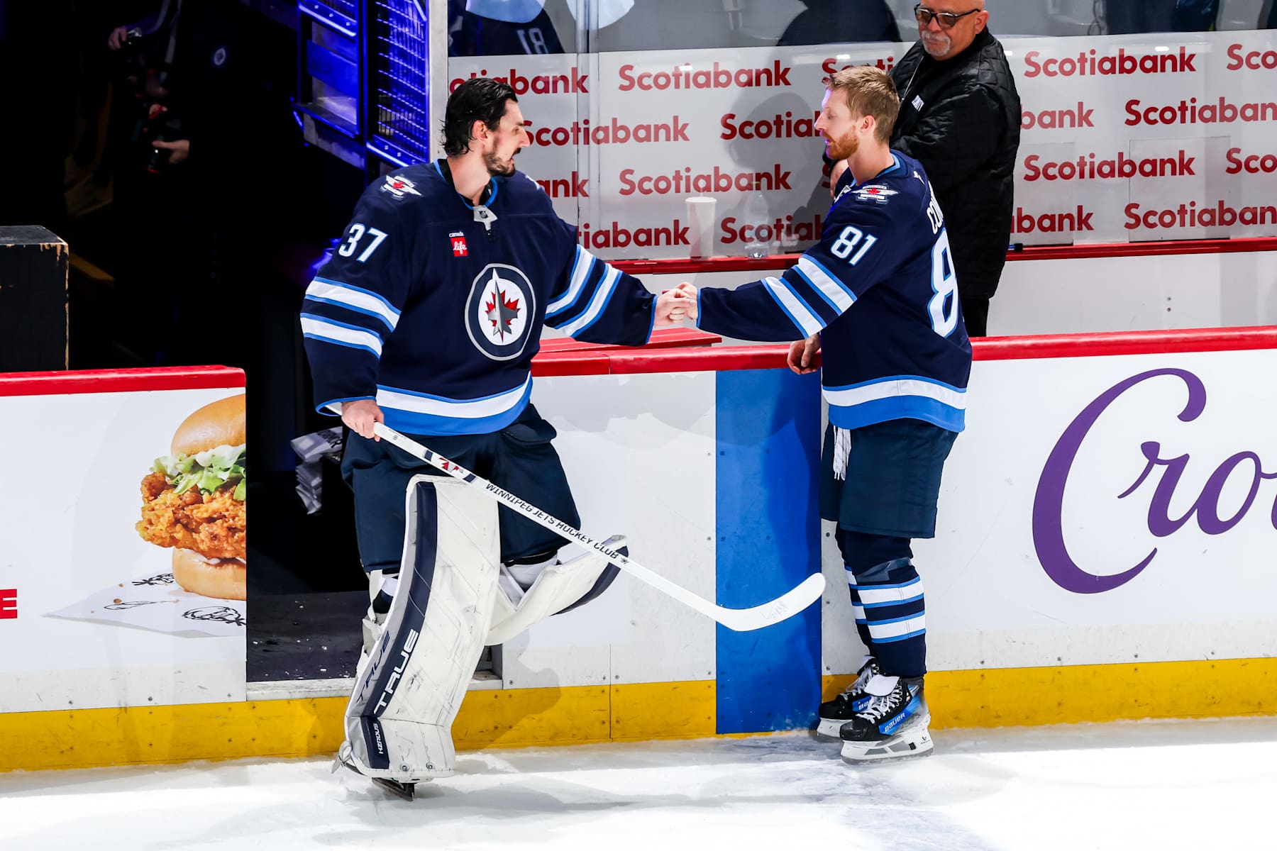 WINNIPEG, CANADA - DECEMBER 14: Goaltender Connor Hellebuyck #37 and Kyle Connor #81 of the Winnipeg Jets share a fist bump after being named first and second star respectively following a 4-2 victory over the Montreal Canadiens at the Canada Life Centre on December 14, 2024 in Winnipeg, Manitoba, Canada. (Photo by Jonathan Kozub/NHLI via Getty Images)