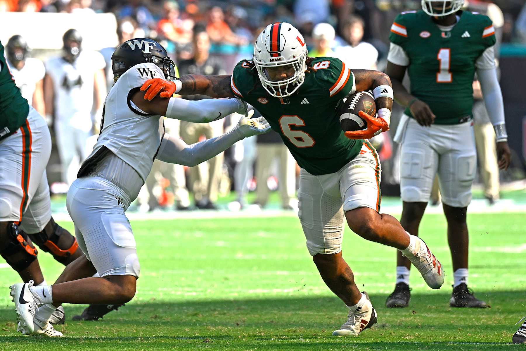MIAMI GARDENS, FL - NOVEMBER 23:  Miami running back Damien Martinez (6) holds off Wake Forest defensive back Evan Slocum (7) while carrying the ball in the first quarter as the Miami Hurricanes faced the Wake Forest  Demon Deacons on November 23, 2024, at Hard Rock Stadium in Miami Gardens, Florida. (Photo by Samuel Lewis/Icon Sportswire via Getty Images)