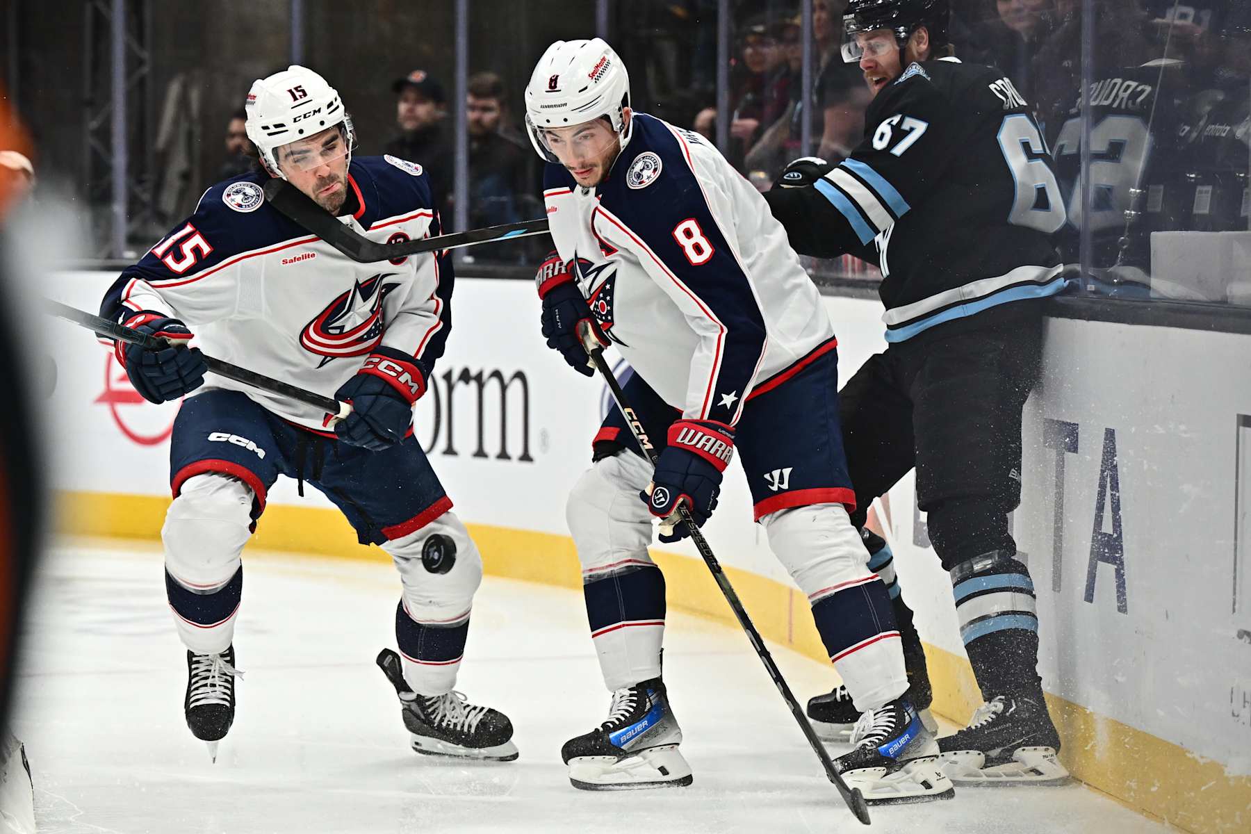 SALT LAKE CITY, UTAH - JANUARY 31: Dante Fabbro #15 of the Columbus Blue Jackets takes a stick to the face from Lawson Crouse #67 of the Utah Hockey Club while battling for a puck with Zach Werenski #8 of the Columbus Blue Jackets in the first period on January 31, 2025 at Delta Center in Salt Lake City, Utah. (Photo by Jamie Sabau/NHLI via Getty Images)