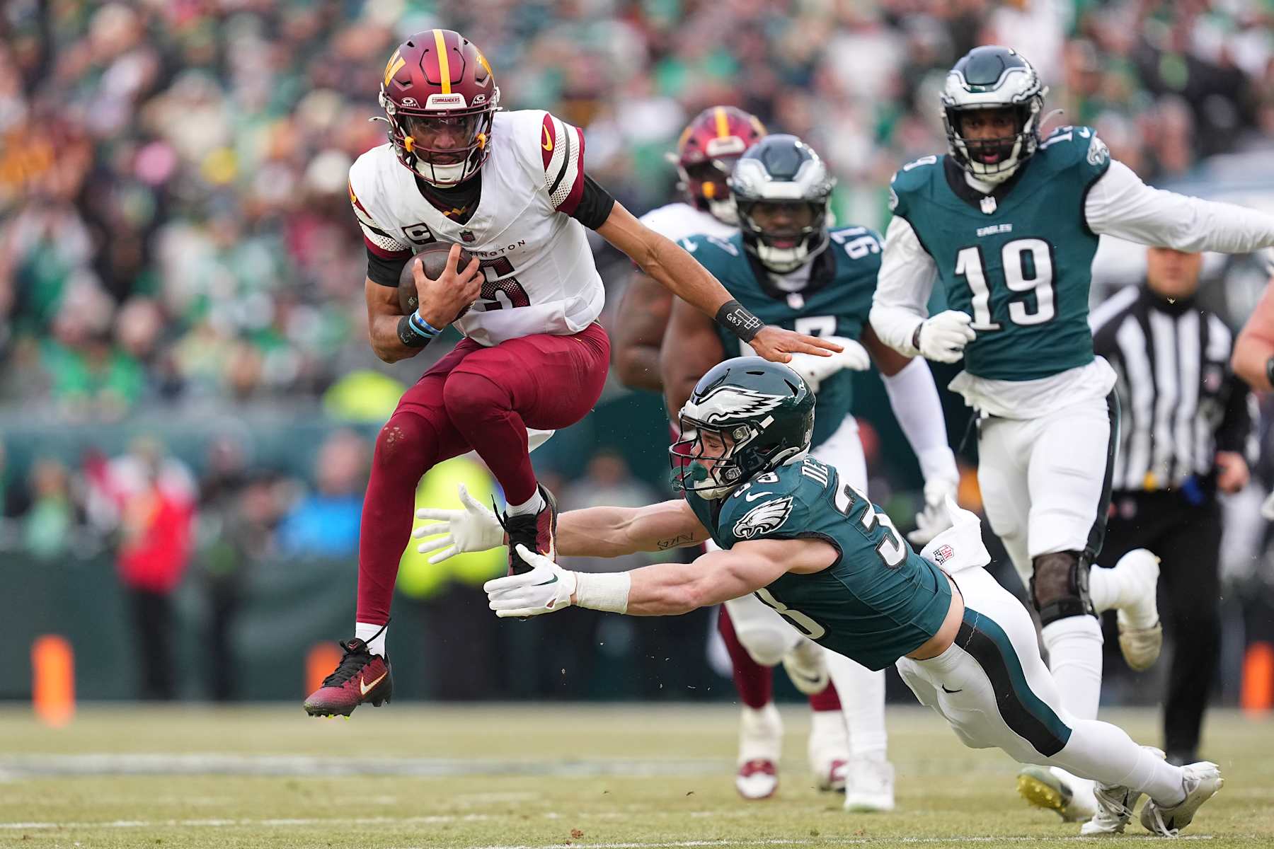 PHILADELPHIA, PENNSYLVANIA - JANUARY 26: Jayden Daniels #5 of the Washington Commanders attempts to break a tackle against Cooper DeJean #33 of the Philadelphia Eagles during the first quarter in the NFC Championship Game at Lincoln Financial Field on January 26, 2025 in Philadelphia, Pennsylvania.  (Photo by Mitchell Leff/Getty Images)