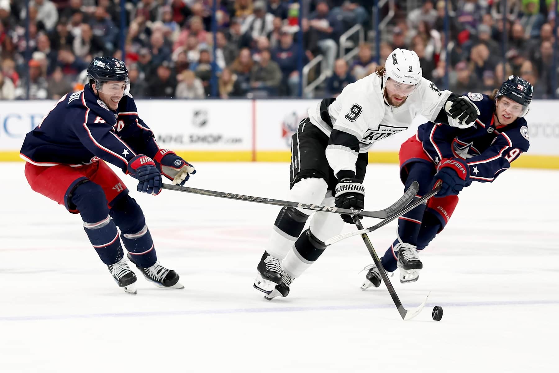 COLUMBUS, OHIO - JANUARY 25: Zach Werenski #8 of the Columbus Blue Jackets and Kent Johnson #91 attempt to steal the puck from Adrian Kempe #9 of the Los Angeles Kings during the second period of the game at Nationwide Arena on January 25, 2025 in Columbus, Ohio. (Photo by Kirk Irwin/NHLI via Getty Images)