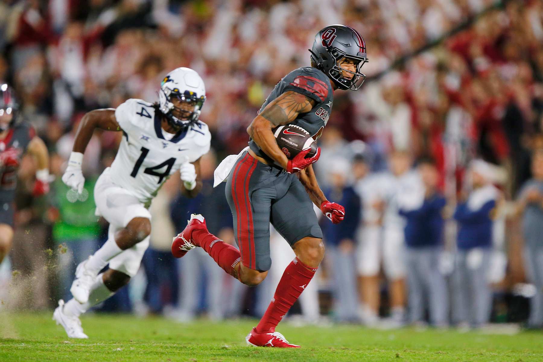 NORMAN, OKLAHOMA - NOVEMBER 11: Wide receiver Nic Anderson #4 of the Oklahoma Sooners runs with a deep pass for 63 yards against linebacker cornerback Malachi Ruffin #14 of the West Virginia Mountaineers in the second quarter at Gaylord Family Oklahoma Memorial Stadium on November 11, 2023 in Norman, Oklahoma. Oklahoma won 59-20. (Photo by Brian Bahr/Getty Images)
