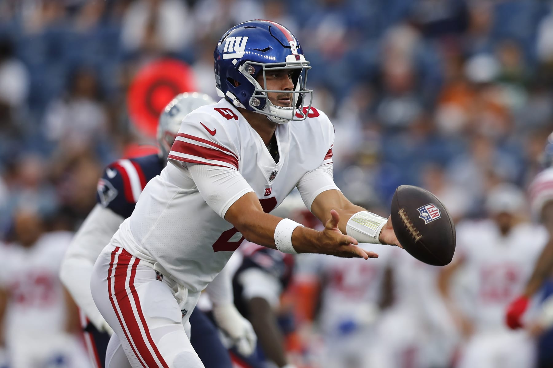 New York Giants quarterback Daniel Jones tosses the ball to running back Saquon Barkley during the first half of the team's preseason NFL football game gainst the New England Patriots, Thursday, Aug. 11, 2022, in Foxborough, Mass. (AP Photo/Michael Dwyer)