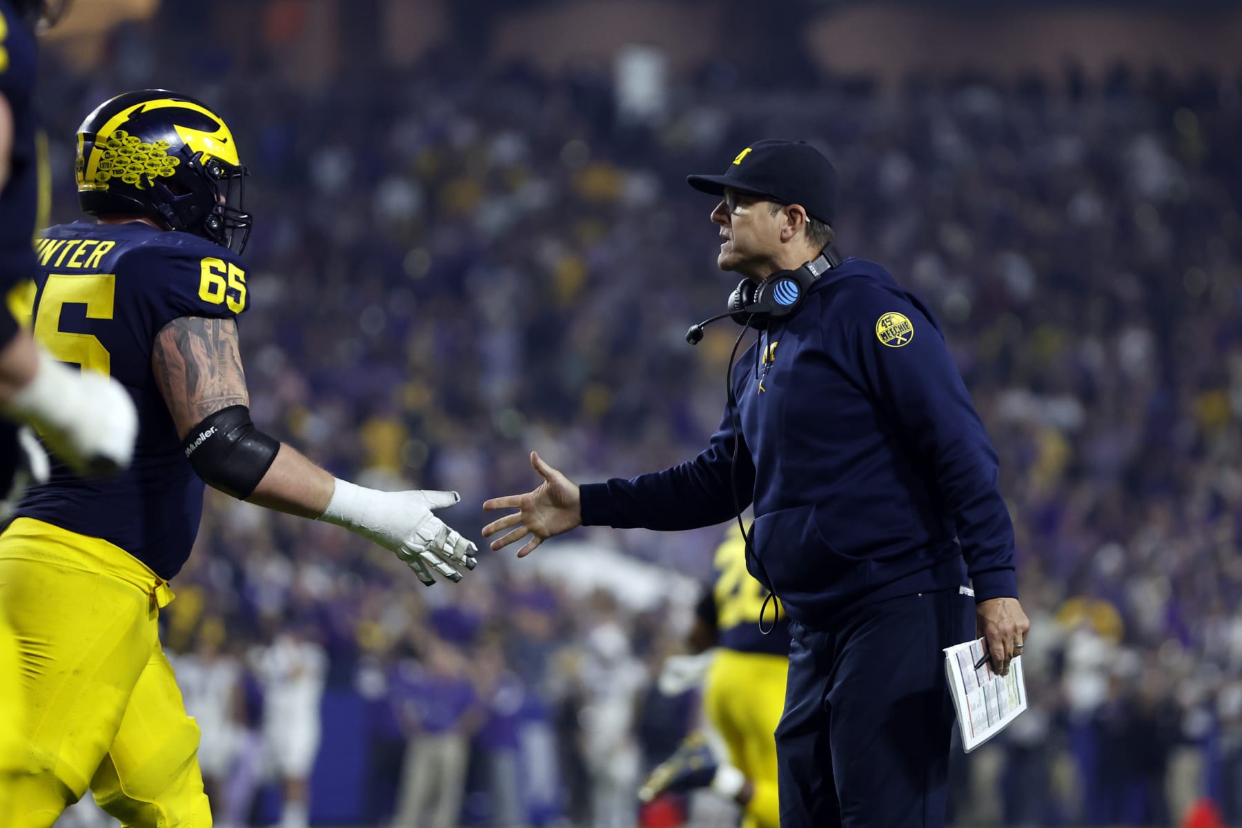 Football Football GLENDALE, ARIZONA - DECEMBER 31: Head coach Jim Harbaugh shakes hands with offensive lineman Zak Zinter #65 of the Michigan Wolverines during the second half of the Vrbo Fiesta Bowl against the TCU Horned Frogs at State Farm Stadium on December 31, 2022 in Glendale, Arizona. The Horned Frogs defeated the Wolverines 51-45. (Photo by Chris Coduto/Getty Images)