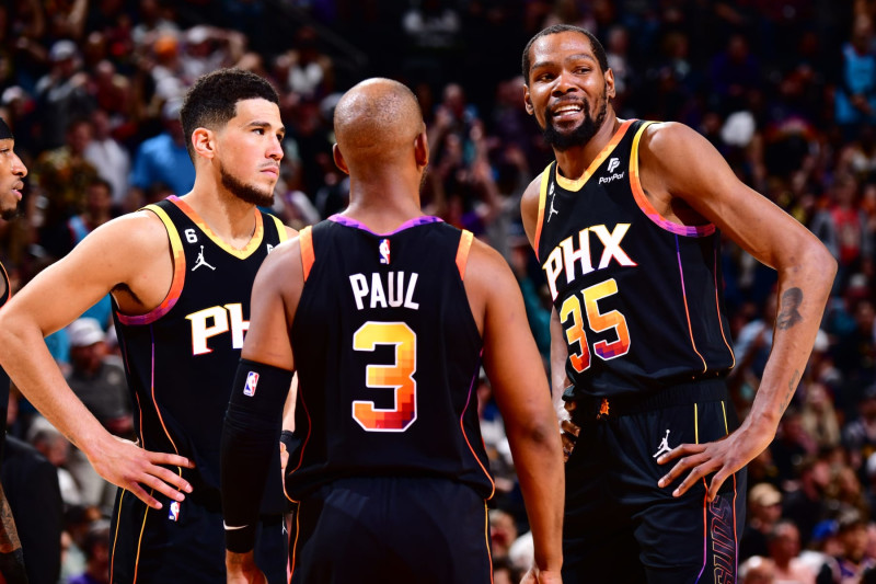 PHOENIX, AZ - APRIL 6:  Devin Booker #1, Chris Paul #3 and Kevin Durant #35 of the Phoenix Suns looks on during the game on April 6, 2023 at Footprint Center in Phoenix, Arizona. NOTE TO USER: User expressly acknowledges and agrees that, by downloading and or using this photograph, user is consenting to the terms and conditions of the Getty Images License Agreement. Mandatory Copyright Notice: Copyright 2023 NBAE (Photo by Barry Gossage/NBAE via Getty Images)