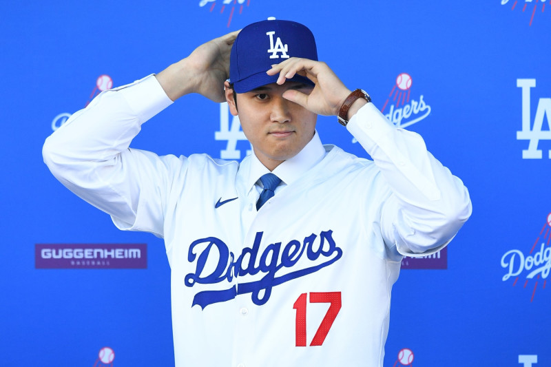 LOS ANGELES, CA - DECEMBER 14: Newly acquired Los Angeles Dodgers designated hitter Shohei Ohtani puts his hat on as he poses for a photo as he is introduced at a press conference on December 14, 2023 at Dodger Stadium in Los Angeles, CA. (Photo by Brian Rothmuller/Icon Sportswire via Getty Images)