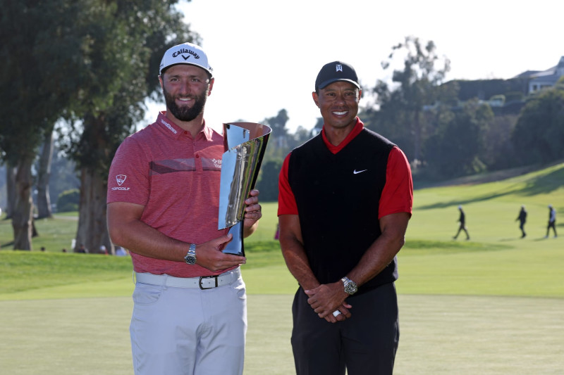 PACIFIC PALISADES, CALIFORNIA - FEBRUARY 19: The Genesis Invitational host, Tiger Woods of the United States, presents the trophy to Jon Rahm of Spain after putting in to win The Genesis Invitational at Riviera Country Club on the 18th green on February 19, 2023 in Pacific Palisades, California. (Photo by Harry How/Getty Images)