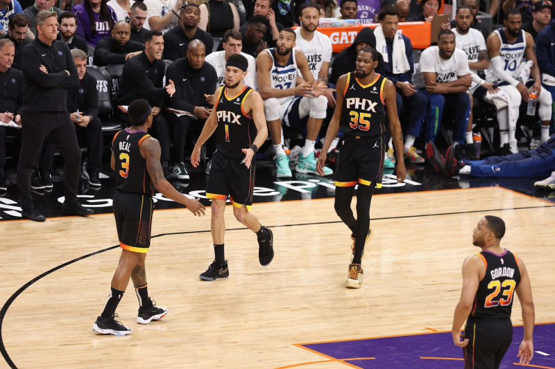 PHOENIX, ARIZONA - APRIL 28: Devin Booker #1 of the Phoenix Suns high fives Bradley Beal #3 and Kevin Durant #35 after scoring against the Minnesota Timberwolves during the first half of game four of the Western Conference First Round Playoffs at Footprint Center on April 28, 2024 in Phoenix, Arizona. NOTE TO USER: User expressly acknowledges and agrees that, by downloading and or using this photograph, User is consenting to the terms and conditions of the Getty Images License Agreement.  (Photo by Christian Petersen/Getty Images)