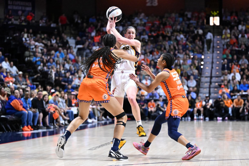 UNCASVILLE, CONNECTICUT - JUNE 10: Caitlin Clark #22 of the Indiana Fever passes the ball against Olivia Nelson-Ododa #10 and Tyasha Harris #52 of the Connecticut Sun during the first half at the Mohegan Sun Arena on June 10, 2024 in Uncasville, Connecticut. NOTE TO USER: User expressly acknowledges and agrees that, by downloading and or using this photograph, User is consenting to the terms and conditions of the Getty Images License Agreement. (Photo by Brian Fluharty/Getty Images)