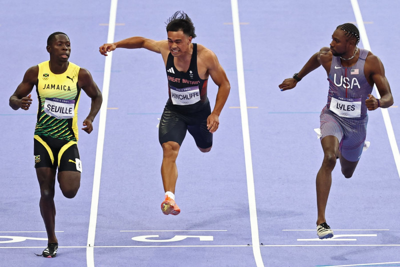 Jamaica's Oblique Seville (L) crosses the finish line ahead of Britain's Louie Hinchliffe and US' Noah Lyles in the men's 100m semi-final of the athletics event at the Paris 2024 Olympic Games at Stade de France in Saint-Denis, north of Paris, on August 4, 2024. (Photo by Anne-Christine POUJOULAT / AFP) (Photo by ANNE-CHRISTINE POUJOULAT/AFP via Getty Images)