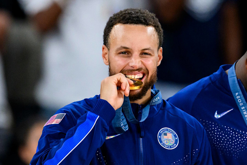 PARIS, FRANCE - AUGUST 11: Gold medalist Stephen Curry of Team United States celebrate on the podium during the Men's basketball medal ceremony on day fifteen of the Olympic Games Paris 2024 at the Bercy Arena on August 11, 2024 in Paris, France. (Photo by Tom Weller/VOIGT/GettyImages)