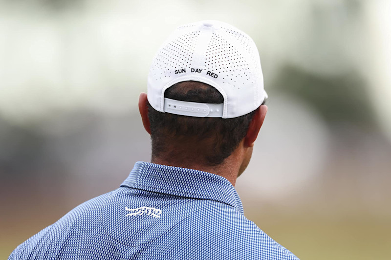 PINEHURST, NORTH CAROLINA - JUNE 10: A detailed view of Sun Day Red logos are seen on a hat and shirt worn by Tiger Woods of the United States during a practice round prior to the U.S. Open at Pinehurst Resort on June 10, 2024 in Pinehurst, North Carolina. (Photo by Gregory Shamus/Getty Images)