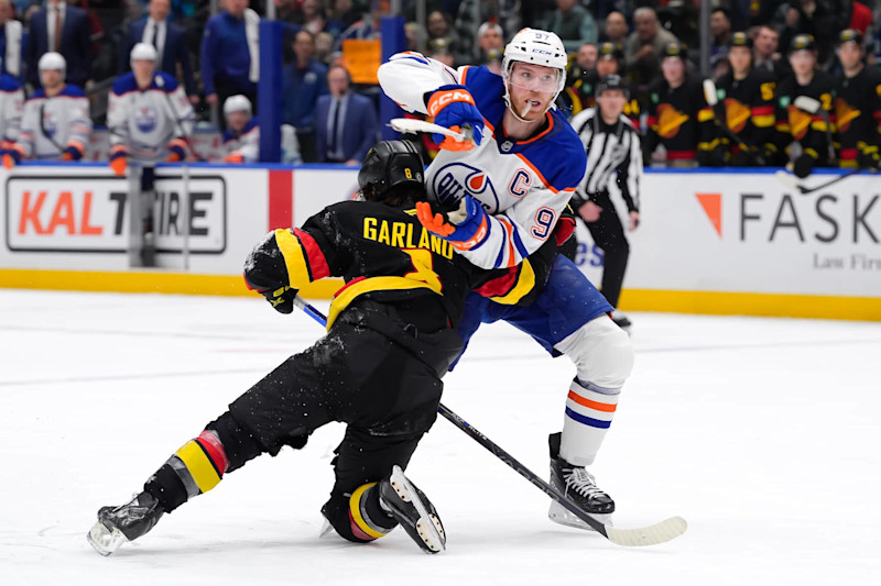 VANCOUVER, CANADA - JANUARY 18: Connor McDavid #97 of the Edmonton Oilers is checked by Conor Garland #8 of the Vancouver Canucks during the third period of their NHL game at Rogers Arena on January 18, 2025 in Vancouver, British Columbia, Canada. (Photo by Derek Cain/Getty Images)