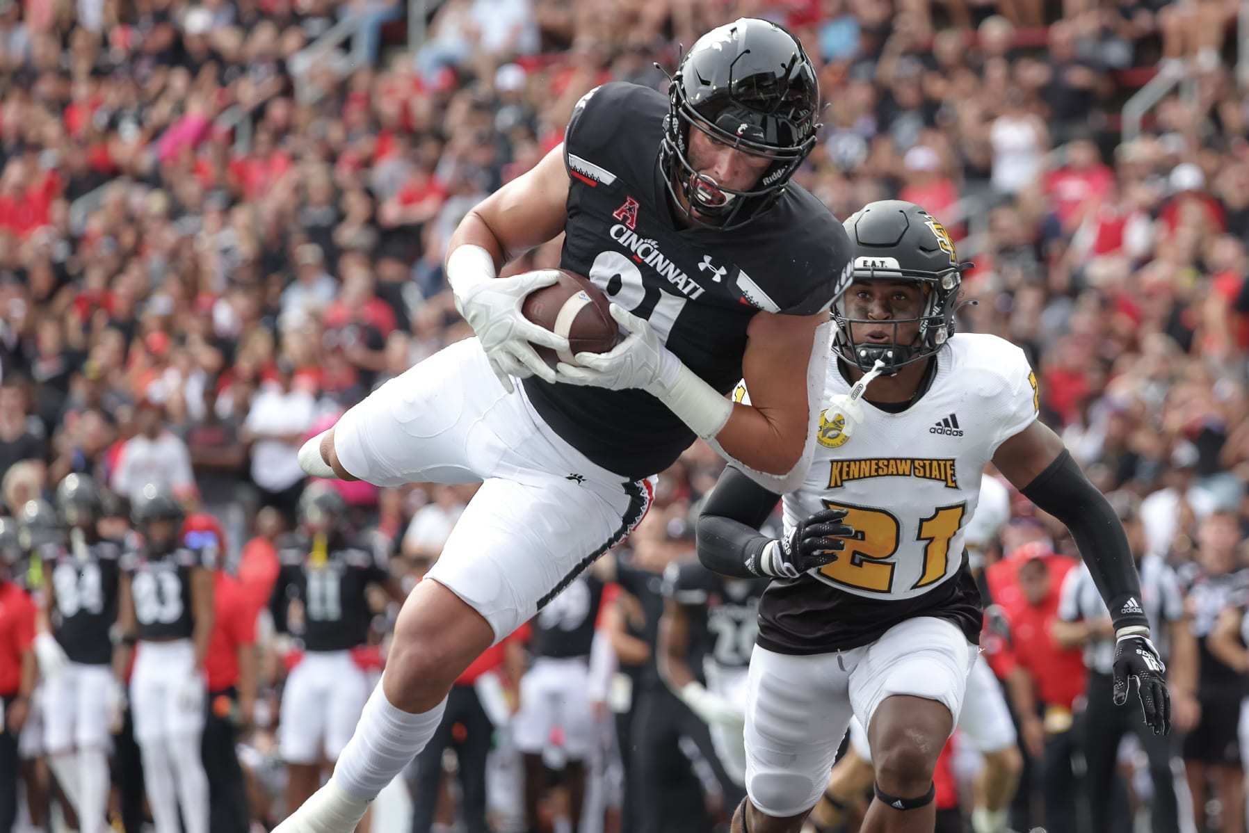 CINCINNATI, OH - SEPTEMBER 10: Josh Whyle #81 of the Cincinnati Bearcats makes a touchdown catch as Markeith Montgomery #21 of the Kennesaw State Owls looks on during the first half at Nippert Stadium on September 10, 2022 in Cincinnati, Ohio. (Photo by Michael Hickey/Getty Images)