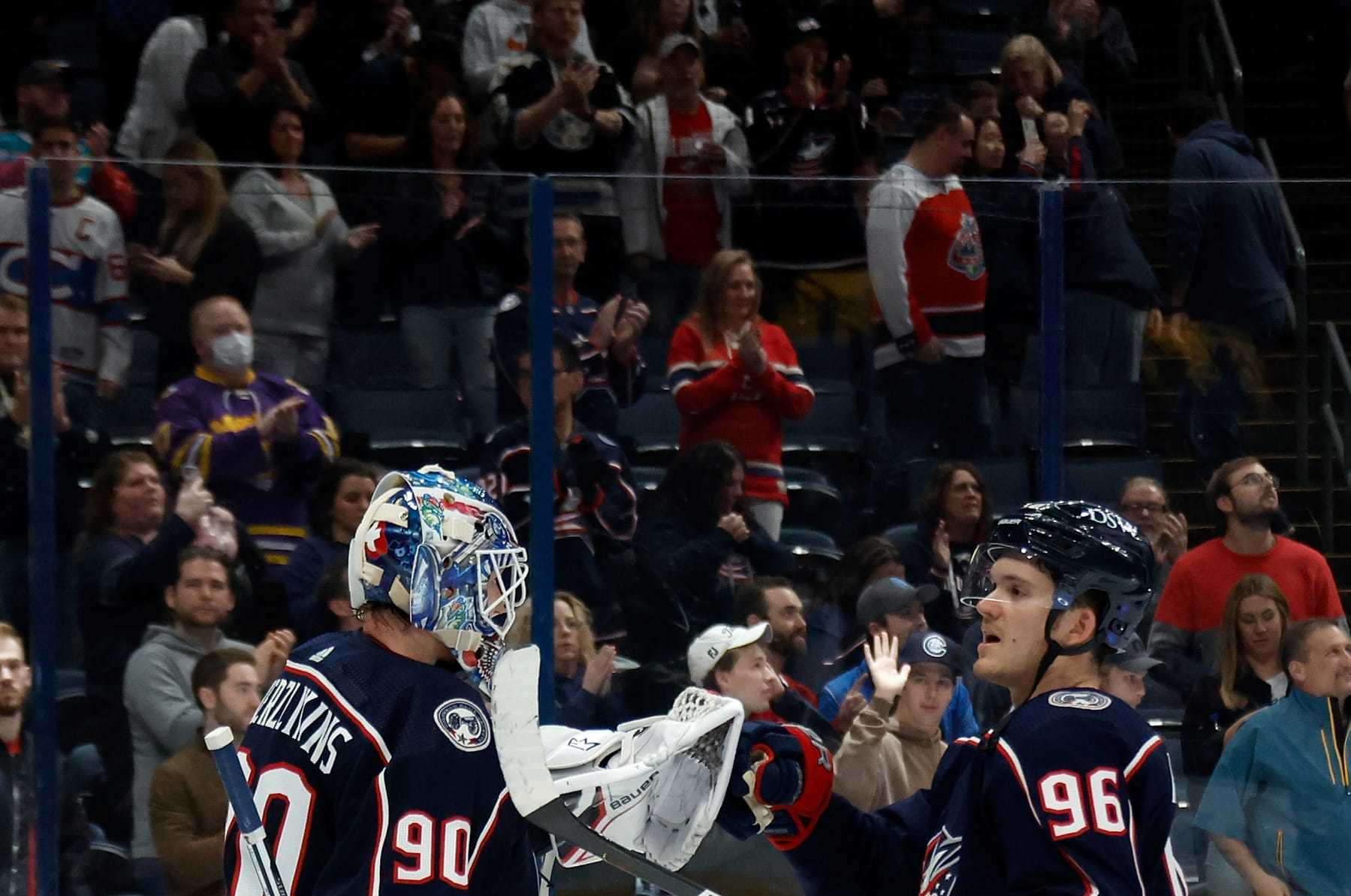 COLUMBUS, OH - APRIL 13: Elvis Merzlikins #90 of the Columbus Blue Jackets is congratulated by Jack Roslovic #96 after defeating the Montreal Canadiens at Nationwide Arena on April 13, 2022 in Columbus, Ohio. Columbus defeated Montreal 5-1. (Photo by Kirk Irwin/Getty Images)