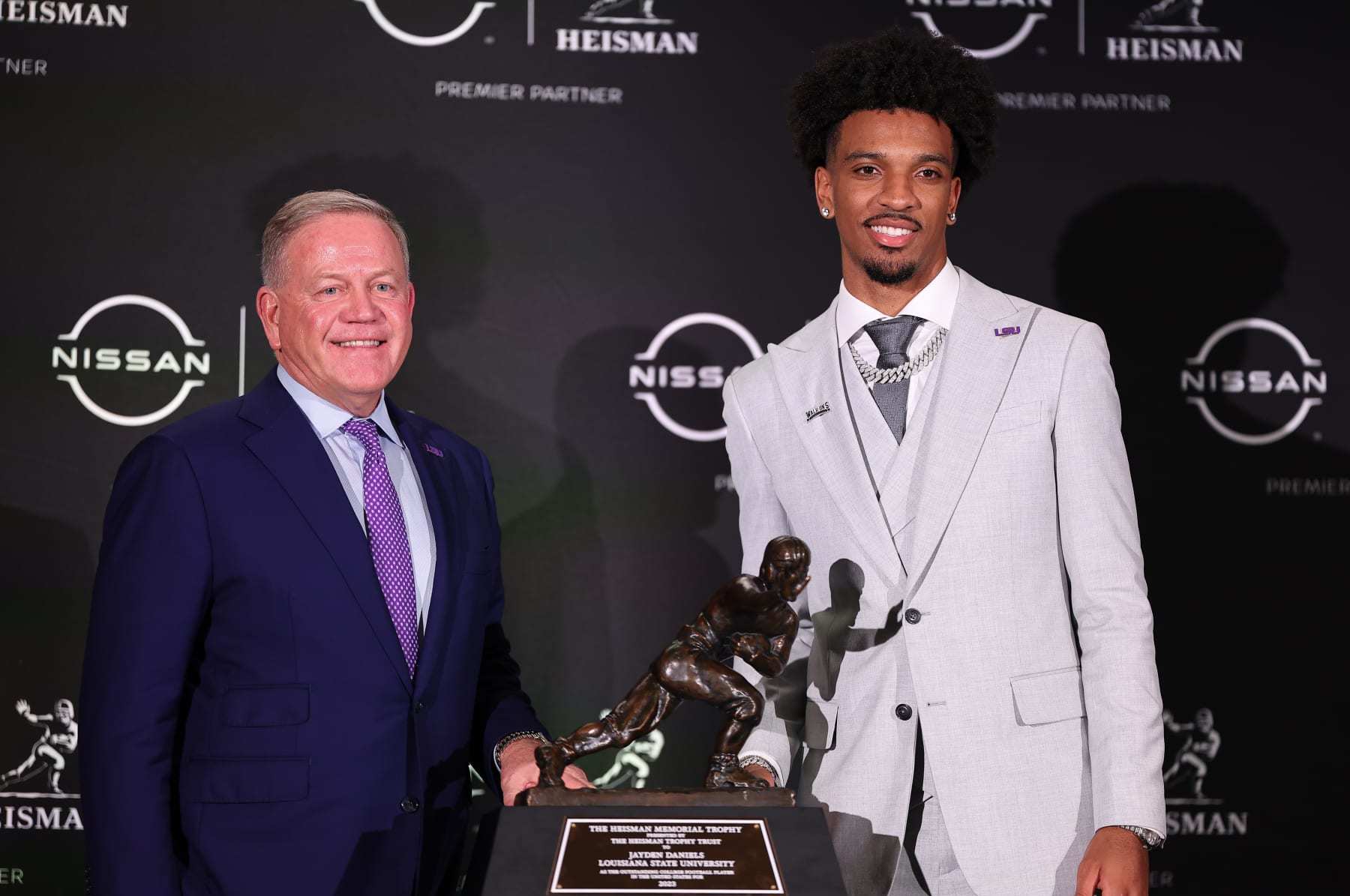 NEW YORK, NY - DECEMBER 09: Jayden Daniels quarterback LSU takes a photo with his head coach Brian Kelly and  the Heisman Trophy after winning it at the press conference at the New York Marriott Marquis on December 9, 2023 in New York City, New York.  (Photo by Rich Graessle/Icon Sportswire via Getty Images)