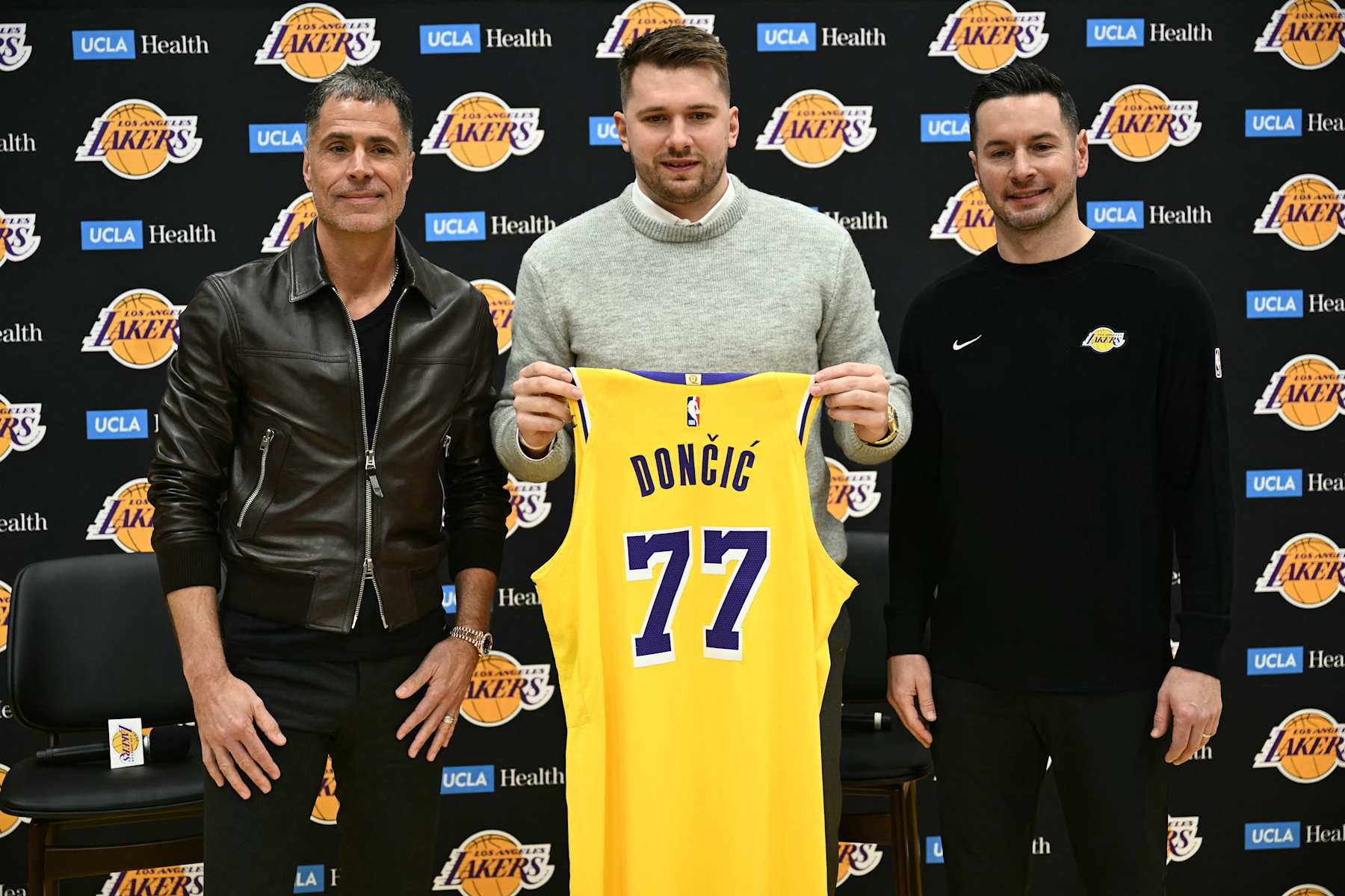Slovenian basketball player Luka Doncic (C) holds up a jersey as he stands alongside Los Angeles Lakers head coach JJ Redick (R) and Los Angeles Lakers general manager Rob Pelinka  during a press conference introducing Doncic as the newest member of the Los Angeles Lakers, at the UCLA Health Training Center, in El Segundo, California on February 4, 2025. Slovenian star Luka Doncic said February 2, 2025 he thought he'd spend his entire NBA career in Dallas, thanking fans in Texas for making it feel like home a day after the Mavericks abruptly traded him to the Los Angeles Lakers. (Photo by Patrick T. Fallon / AFP) (Photo by PATRICK T. FALLON/AFP via Getty Images)          