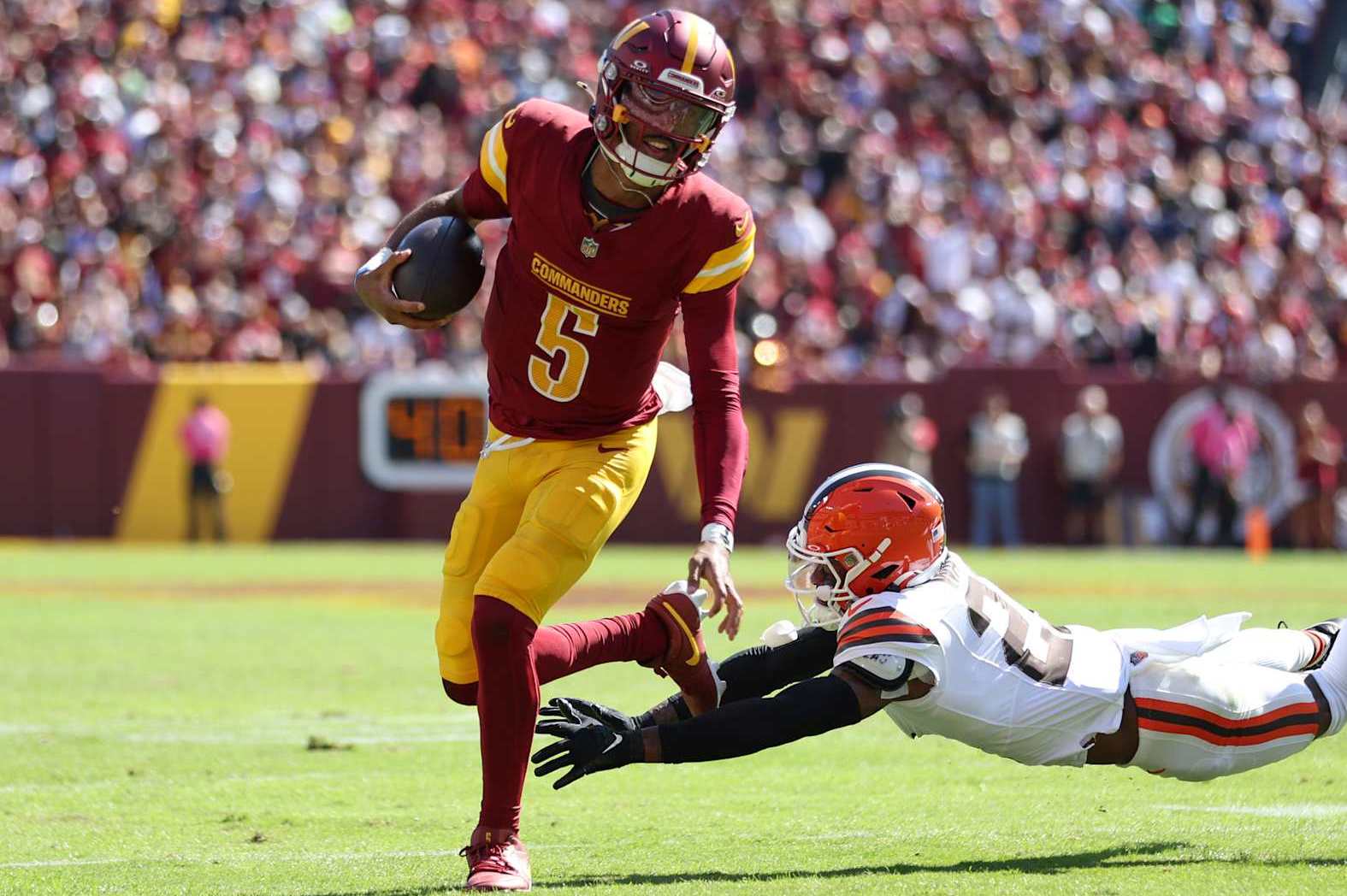 LANDOVER, MARYLAND - OCTOBER 06: Jayden Daniels #5 of the Washington Commanders runs the ball as Denzel Ward #21 of the Cleveland Browns attempts to tackle during the first half at FedExField on October 06, 2024 in Landover, Maryland. (Photo by Patrick Smith/Getty Images)
