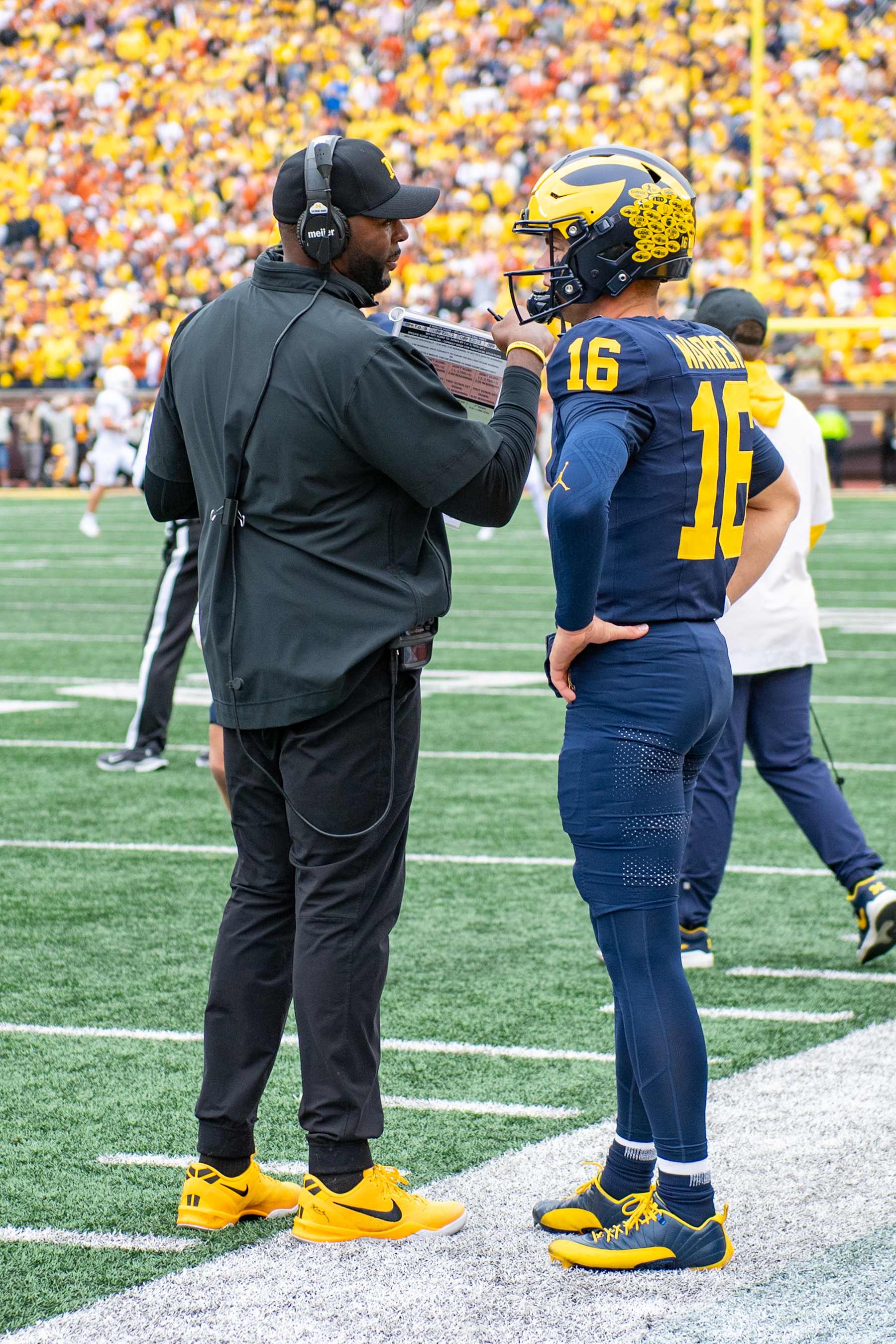 ANN ARBOR, MICHIGAN - SEPTEMBER 07: Head Football Coach Sherrone Moore (L) and Davis Warren #16 of the Michigan Wolverines chat during a timeout in the first half of a college football game against the Texas Longhorns at Michigan Stadium on September 07, 2024 in Ann Arbor, Michigan. (Photo by Aaron J. Thornton/Getty Images)