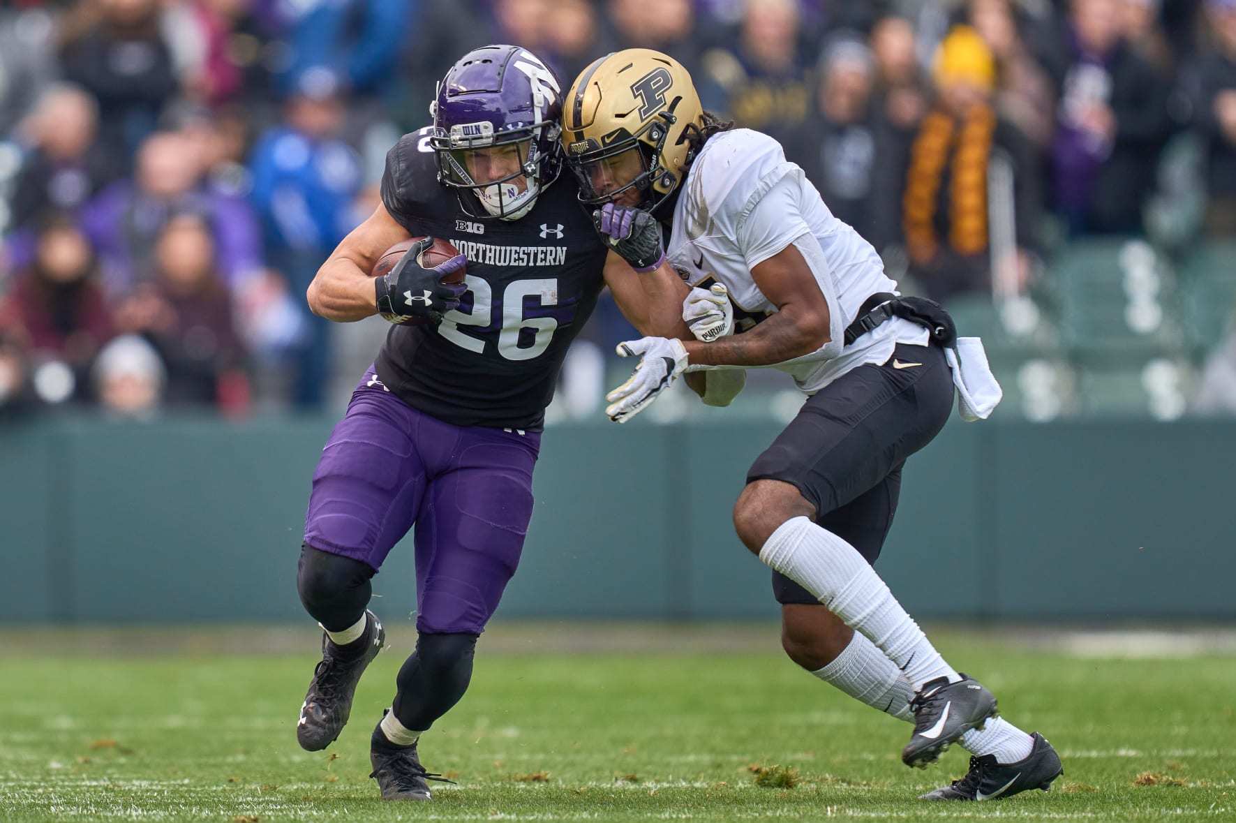 CHICAGO, IL - NOVEMBER 20: Northwestern Wildcats running back Evan Hull (26) battles with Purdue Boilermakers safety Marvin Grant (4) during a game between the Northwestern Wildcats and the Purdue Boilermakers on November 20, 2021 at Wrigley Field in Chicago, IL. (Photo by Robin Alam/Icon Sportswire via Getty Images)