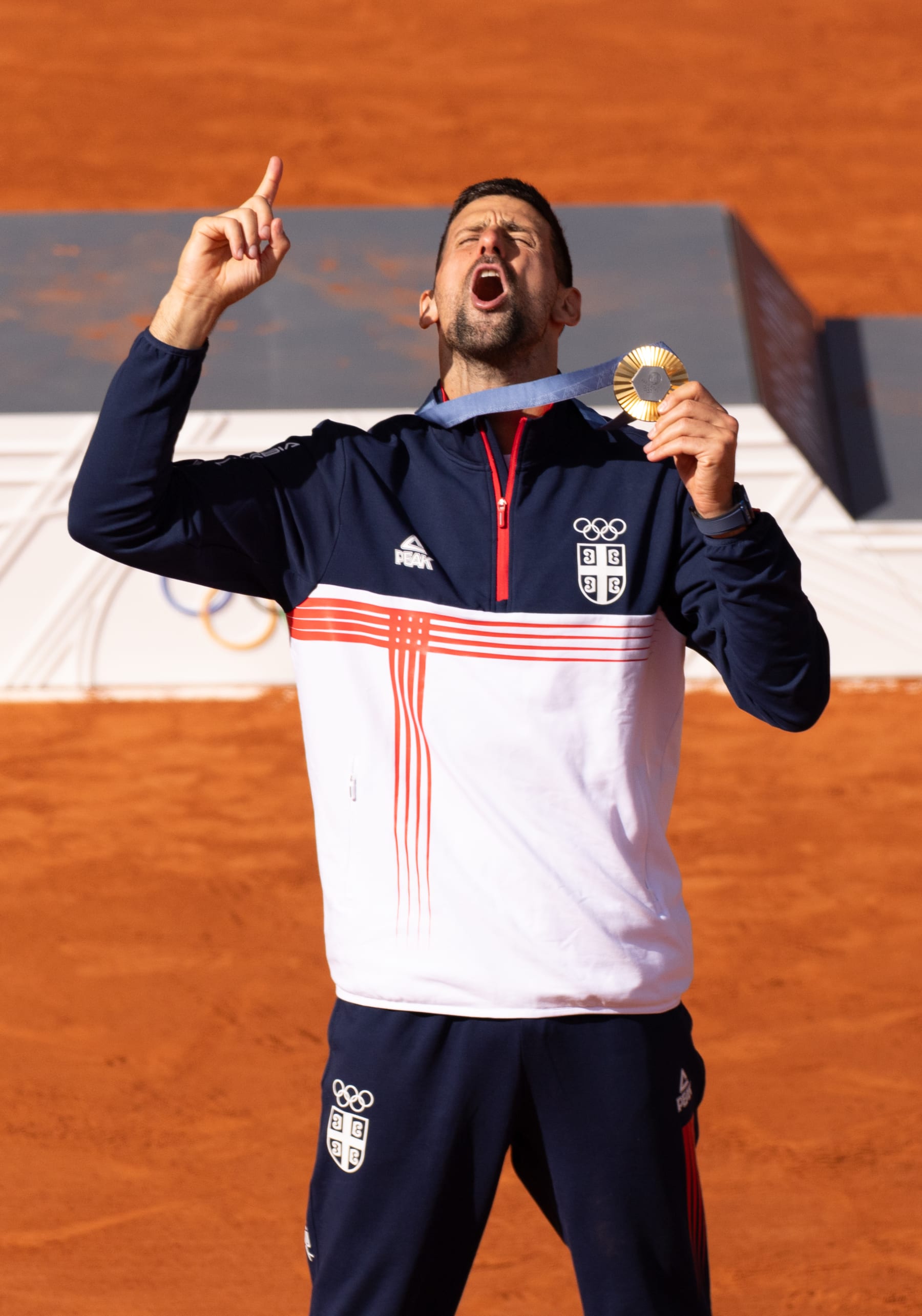 Gold medallist Novak Djokovic of Team Serbia sings the Serbian National anthem on the podium during the Tennis Men's Singles medal ceremony after the Tennis Men's Singles Gold medal match on day nine of the Olympic Games Paris 2024 at Roland Garros on August 04, 2024 in Paris, France. (Photo by Tnani Badreddine/DeFodi Images via Getty Images)