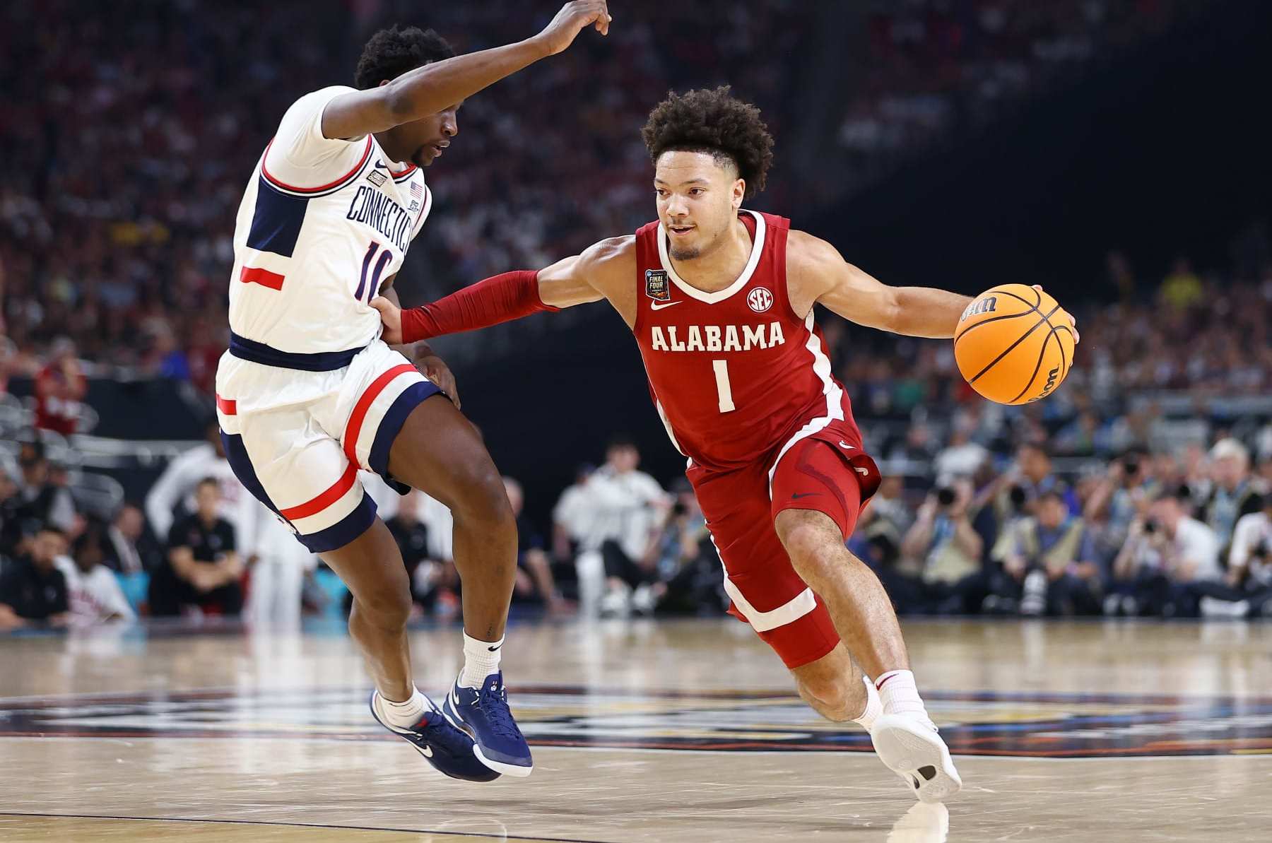 GLENDALE, ARIZONA - APRIL 06: Mark Sears #1 of the Alabama Crimson Tide dribbles the ball around Hassan Diarra #10 of the Connecticut Huskies during the first half in the NCAA Men’s Basketball Tournament Final Four semifinal game at State Farm Stadium on April 06, 2024 in Glendale, Arizona. (Photo by Jamie Schwaberow/NCAA Photos via Getty Images)