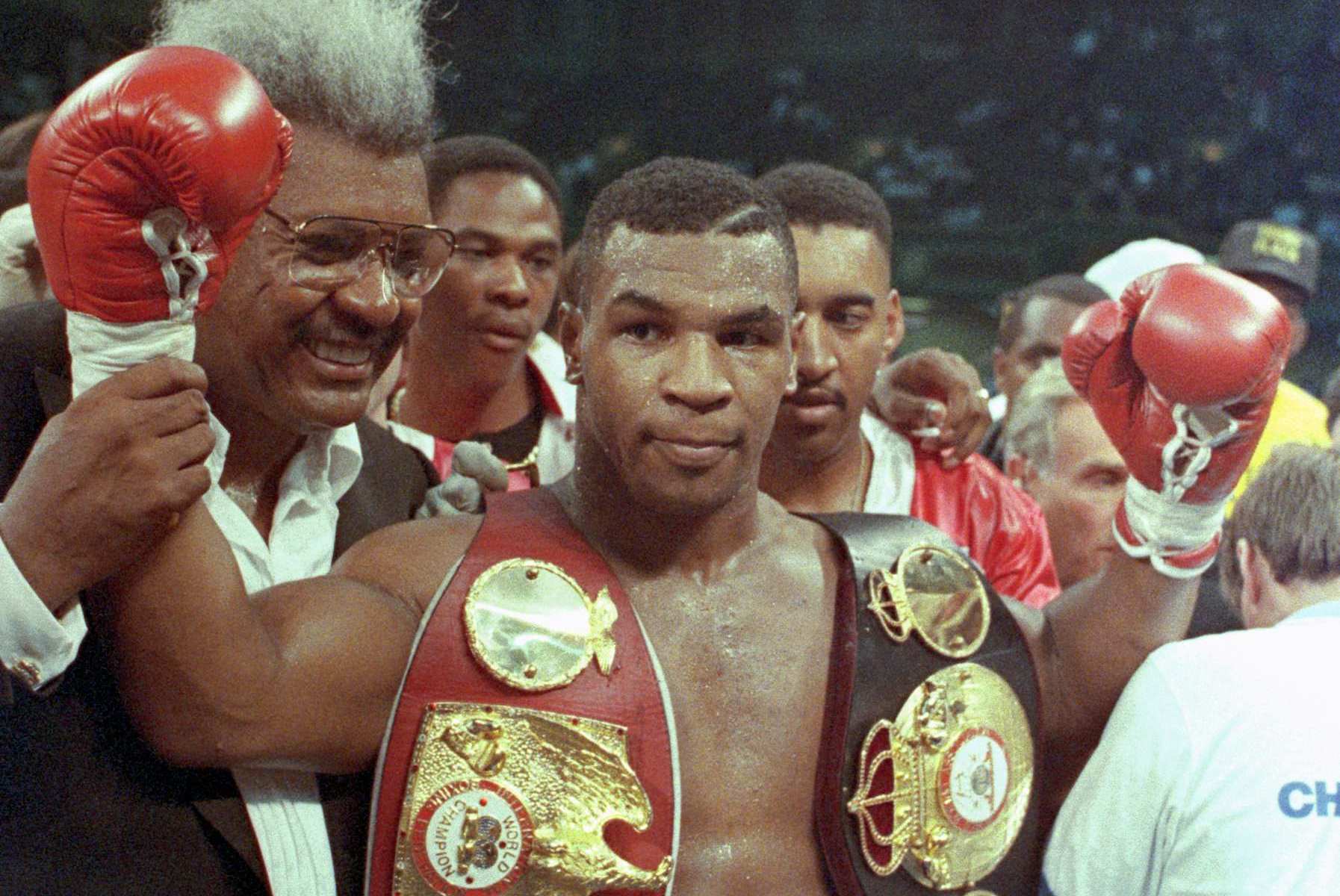 Mike Tyson celebrates his victory over Carl Williams as boxing promoter Don King Walks by his side.