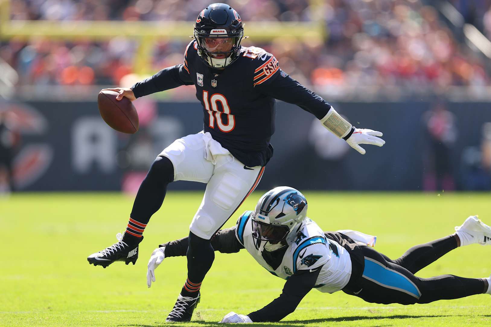 CHICAGO, ILLINOIS - OCTOBER 06: Caleb Williams #18 of the Chicago Bears breaks a tackle from Nick Scott #21 of the Carolina Panthers during the second quarter at Soldier Field on October 06, 2024 in Chicago, Illinois. (Photo by Michael Reaves/Getty Images)