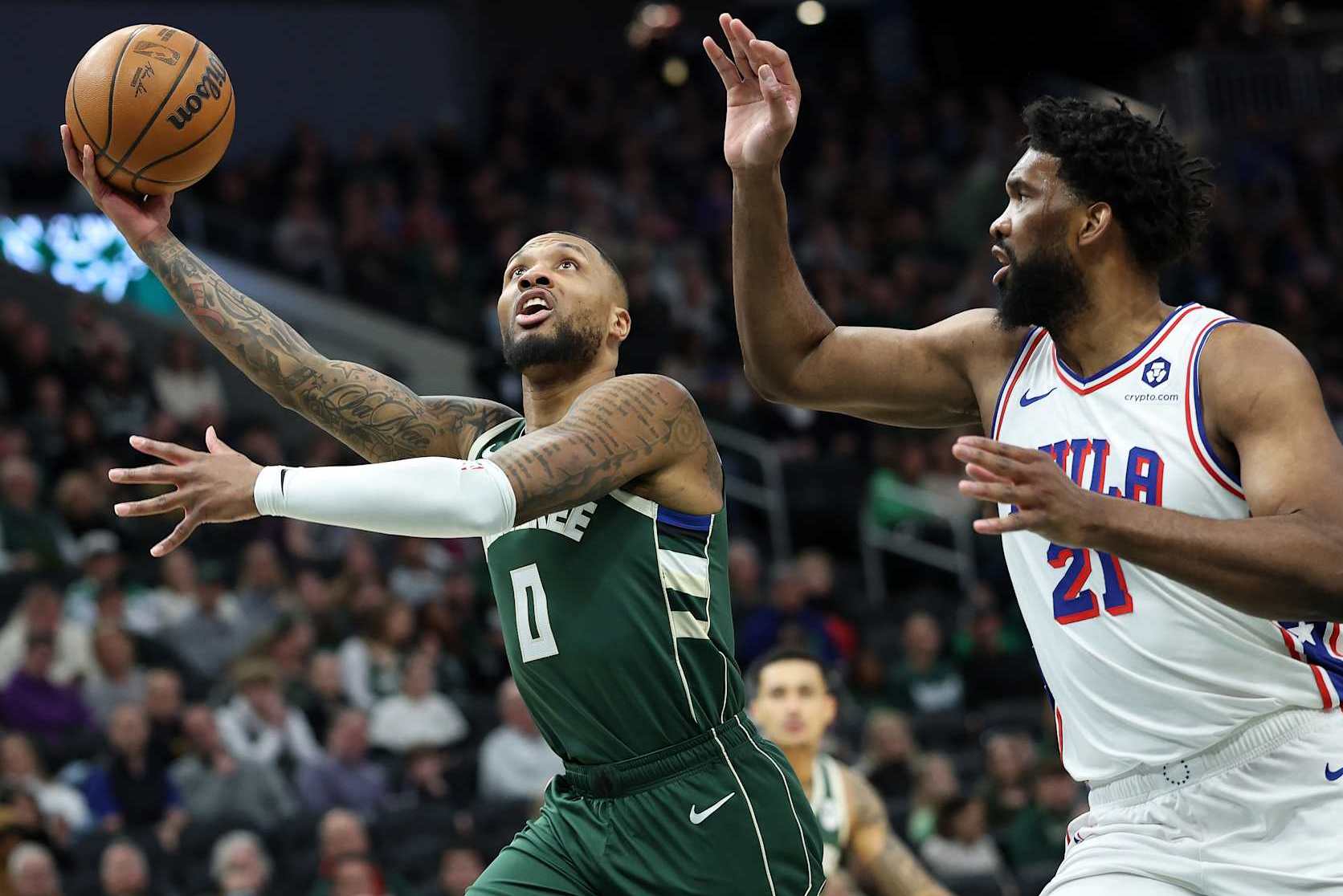 MILWAUKEE, WISCONSIN - FEBRUARY 09: Damian Lillard #0 of the Milwaukee Bucks drives to the basket against Joel Embiid #21 of the Philadelphia 76ers during the first half of a game at Fiserv Forum on February 09, 2025 in Milwaukee, Wisconsin. NOTE TO USER: User expressly acknowledges and agrees that, by downloading and or using this photograph, User is consenting to the terms and conditions of the Getty Images License Agreement. (Photo by Stacy Revere/Getty Images)