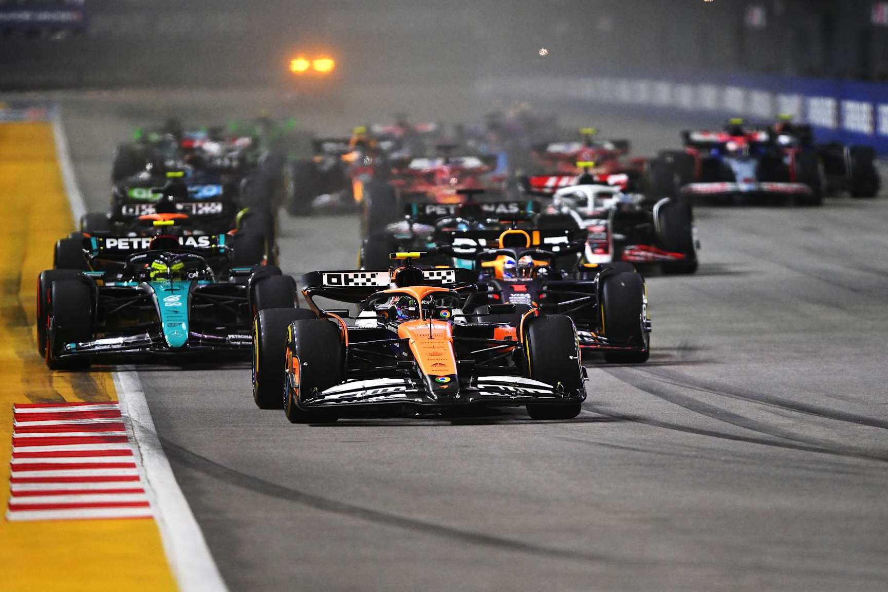 SINGAPORE, SINGAPORE - SEPTEMBER 22: Lando Norris of Great Britain driving the (4) McLaren MCL38 Mercedes leads Max Verstappen of the Netherlands driving the (1) Oracle Red Bull Racing RB20 and the rest of the field into turn one at the start during the F1 Grand Prix of Singapore at Marina Bay Street Circuit on September 22, 2024 in Singapore, Singapore. (Photo by Rudy Carezzevoli/Getty Images)