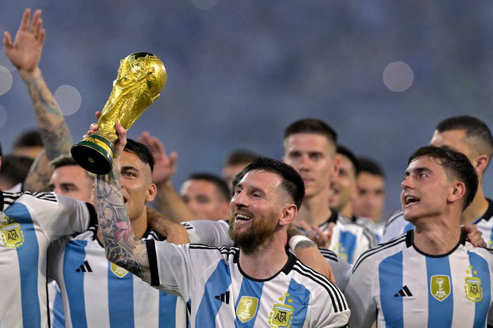 Argentina's forward Lionel Messi (C) raises a replica of the World Cup trophy next to his teammates during a recognition ceremony for the World Cup-winning players, following the friendly football match between Argentina and Curacao at the Madre de Ciudades stadium in Santiago del Estero, in northern Argentina, on March 28, 2023. (Photo by JUAN MABROMATA / AFP) (Photo by JUAN MABROMATA/AFP via Getty Images)