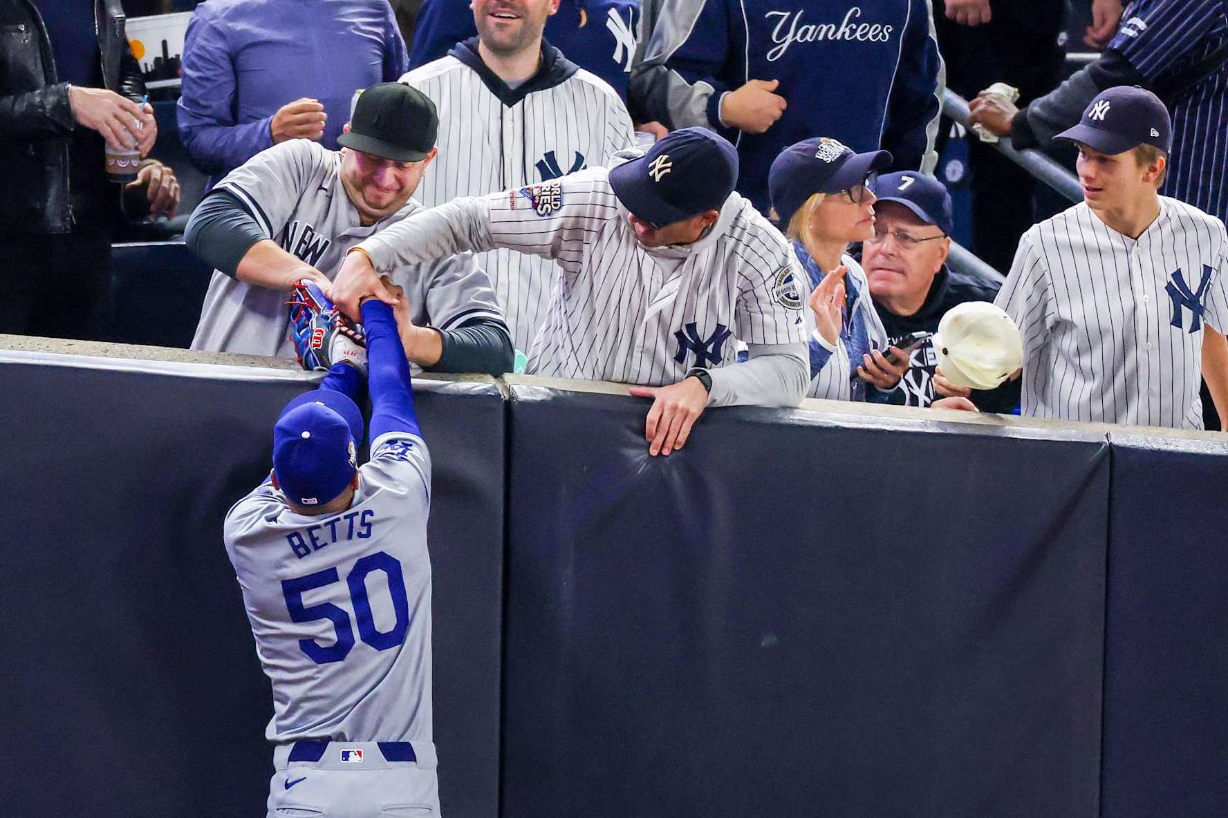 NEW YORK, NEW YORK - OCTOBER 29:  Fans Austin Capobianco (L) and John Peter (R) interfere with Mookie Betts #50 of the Los Angeles Dodgers as he attempts to catch a fly ball in foul territory during the first inning of Game Four of the 2024 World Series against the New York Yankees at Yankee Stadium on October 29, 2024 in the Bronx borough of New York City. The play resulted in an out. (Photo by Al Bello/Getty Images)
