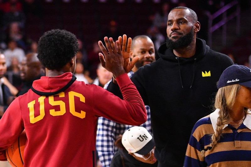 LOS ANGELES, CA - JANUARY 06: USC Trojans guard Bronny James (6) give his dad Lebron James a high five before the college basketball game between the Stanford Cardinal and the USC Trojans on January 6, 2024 at Galen Center in Los Angeles, CA. (Photo by Brian Rothmuller/Icon Sportswire via Getty Images)