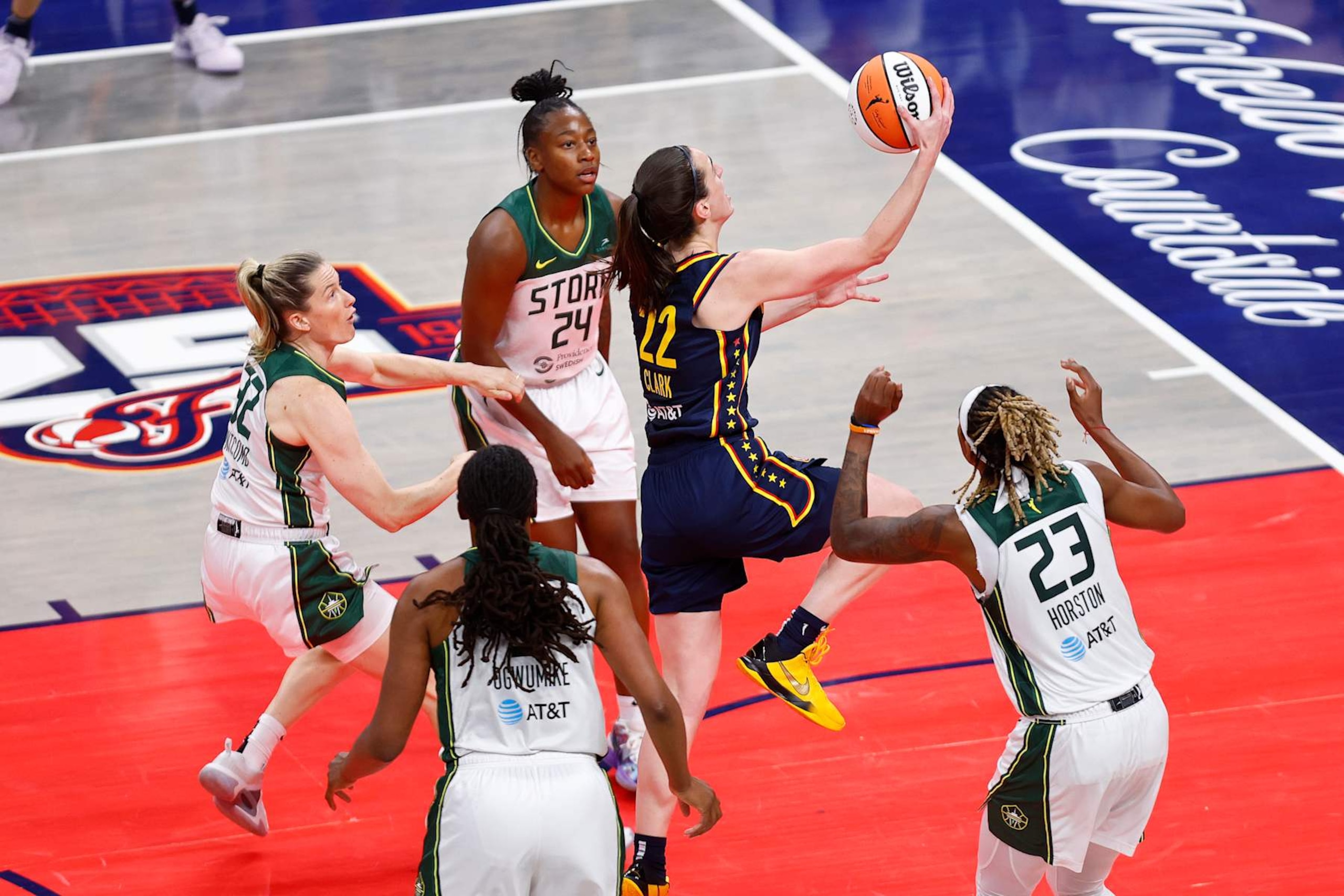 INDIANAPOLIS, IN - AUGUST 18: Indiana Fever guard Caitlin Clark (22) drives past the Seattle Storm defenders and goes up with her layup for two in the second quarter of play during a WNBA game between the Seattle Storm and the Indiana Fever on August 18, 2024 at Gainbridge Fieldhouse in Indianapolis, IN. (Photo by Jeffrey Brown/Icon Sportswire via Getty Images)