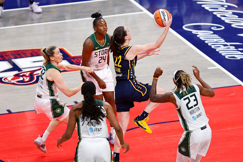 INDIANAPOLIS, IN - AUGUST 18: Indiana Fever guard Caitlin Clark (22) drives past the Seattle Storm defenders and goes up with her layup for two in the second quarter of play during a WNBA game between the Seattle Storm and the Indiana Fever on August 18, 2024 at Gainbridge Fieldhouse in Indianapolis, IN. (Photo by Jeffrey Brown/Icon Sportswire via Getty Images)