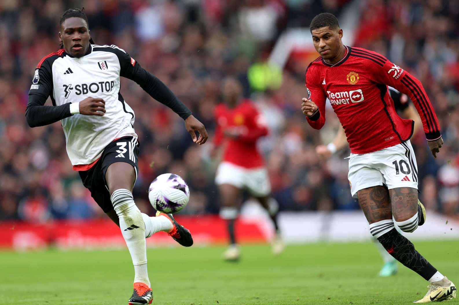 MANCHESTER, ENGLAND - FEBRUARY 24: Calvin Bassey and Marcus Rashford of Manchester United run for the ball during the Premier League match between Manchester United and Fulham FC at Old Trafford on February 24, 2024 in Manchester, England. (Photo by Clive Brunskill/Getty Images)
