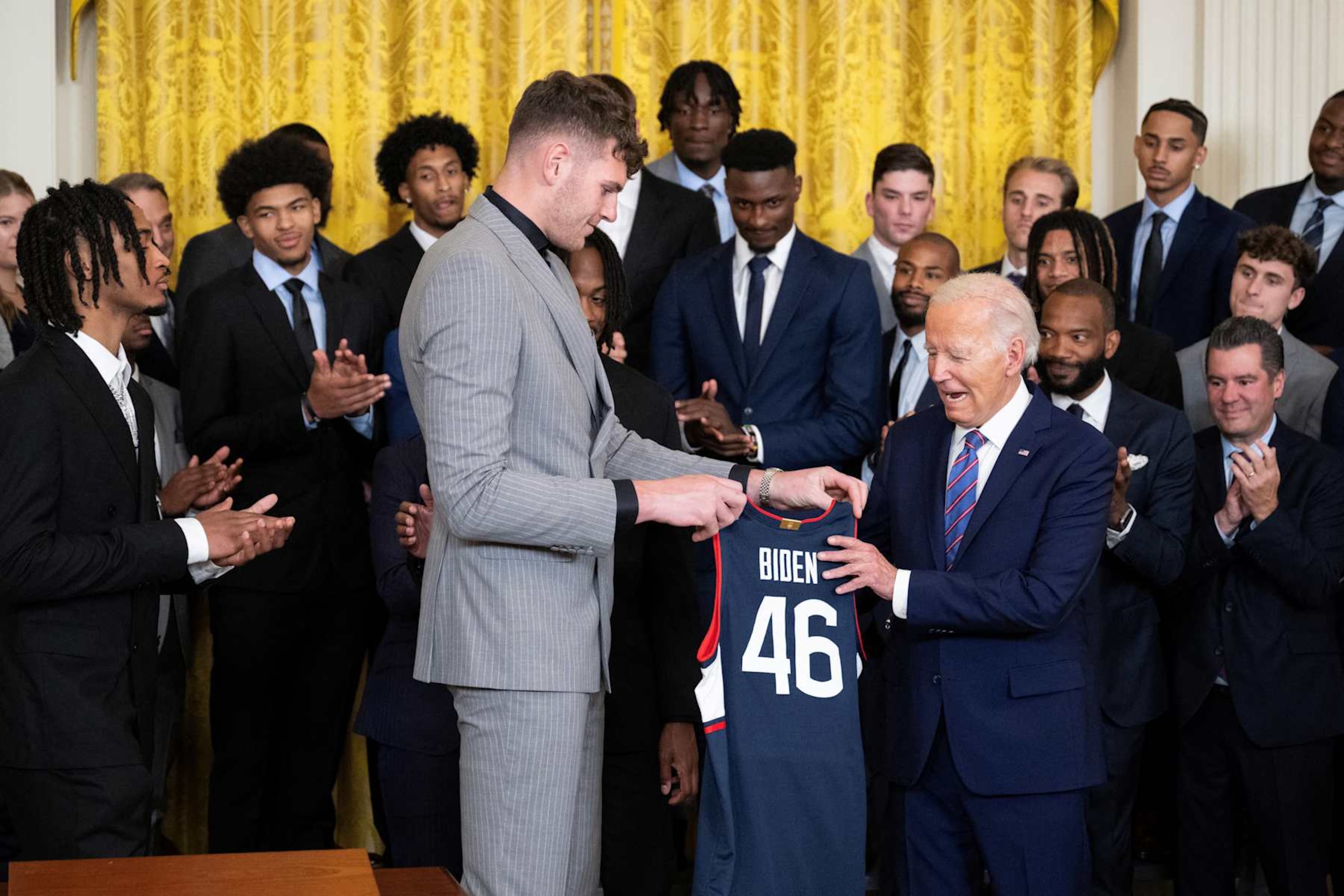 Donovan Clingan gives a jersey to US President Joe Biden during an event to celebrate the University of Connecticut men's basketball team for their 2023-2024 championship season in the East Room of the White House on September 10, 2024 in Washington, DC. (Photo by Drew ANGERER / AFP) (Photo by DREW ANGERER/AFP via Getty Images)